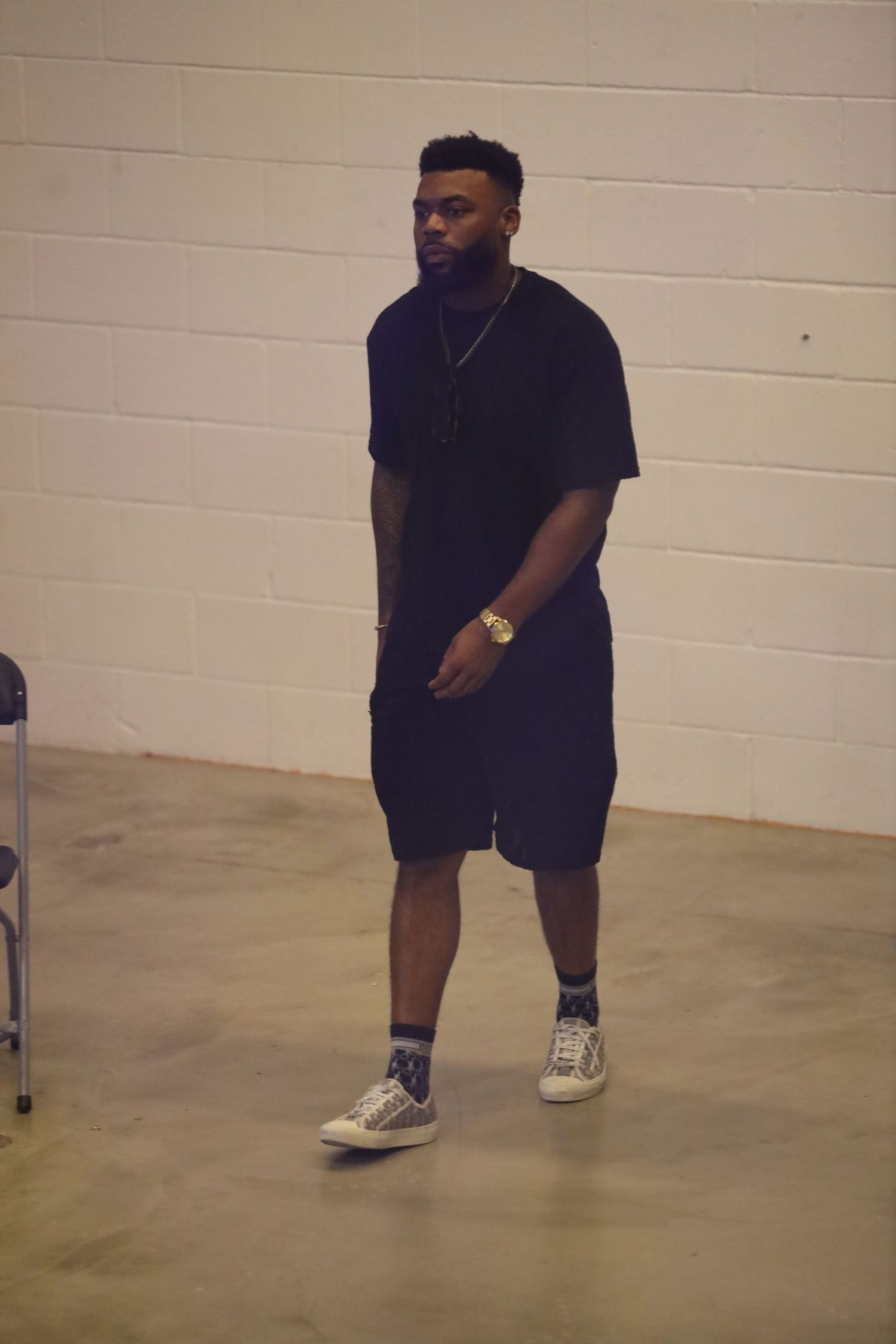 Casual street style look with black t-shirt and shorts against white wall background.