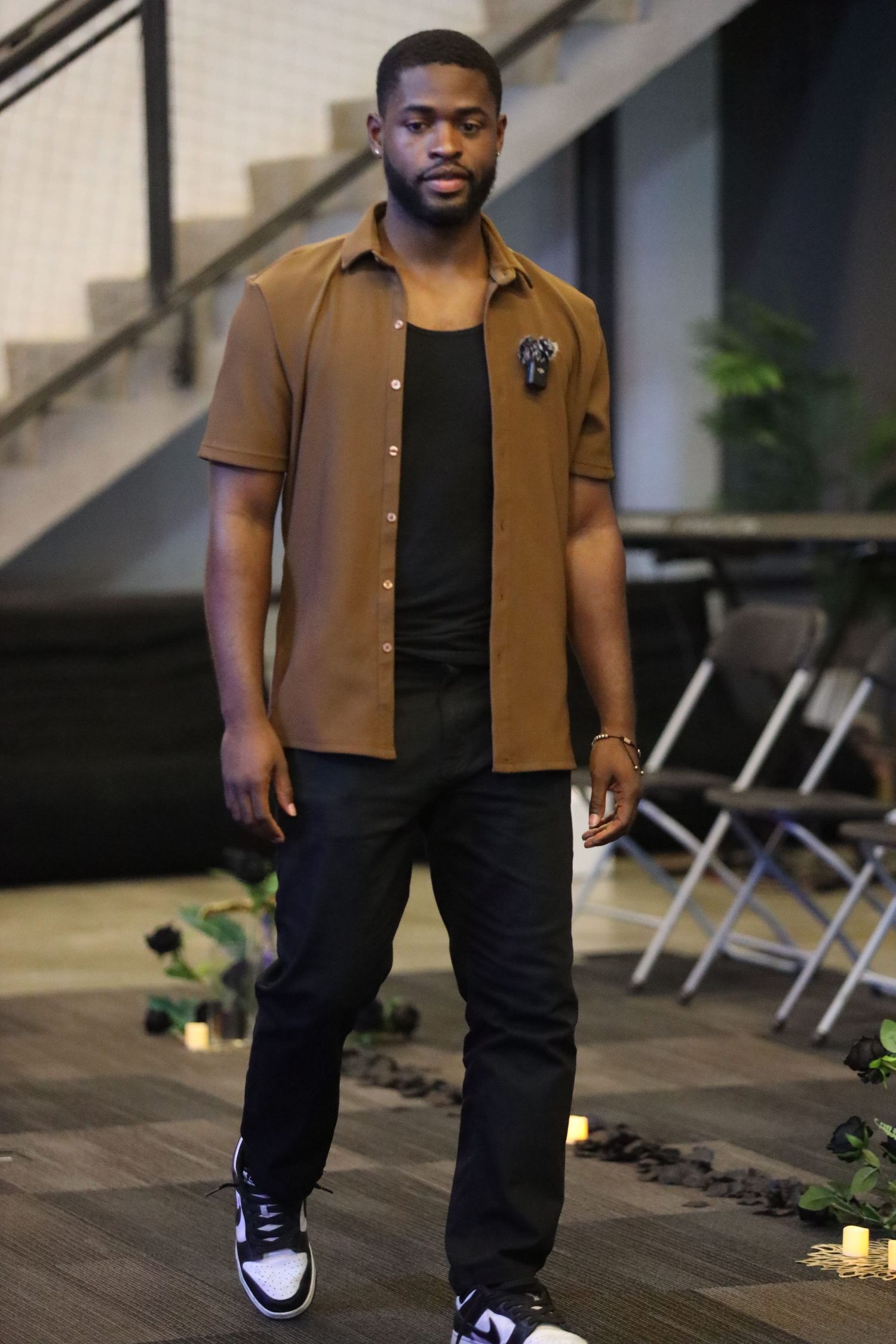 Stylish casual outfit featuring brown button-up shirt and dark pants in indoor setting.