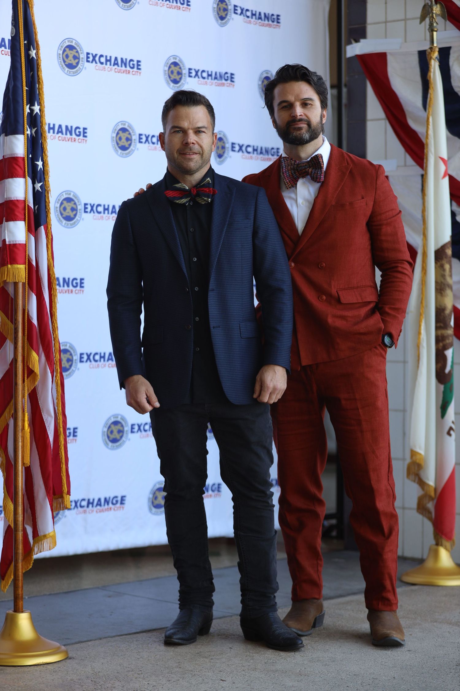 Two people in contrasting suits stand together at Exchange branded event.