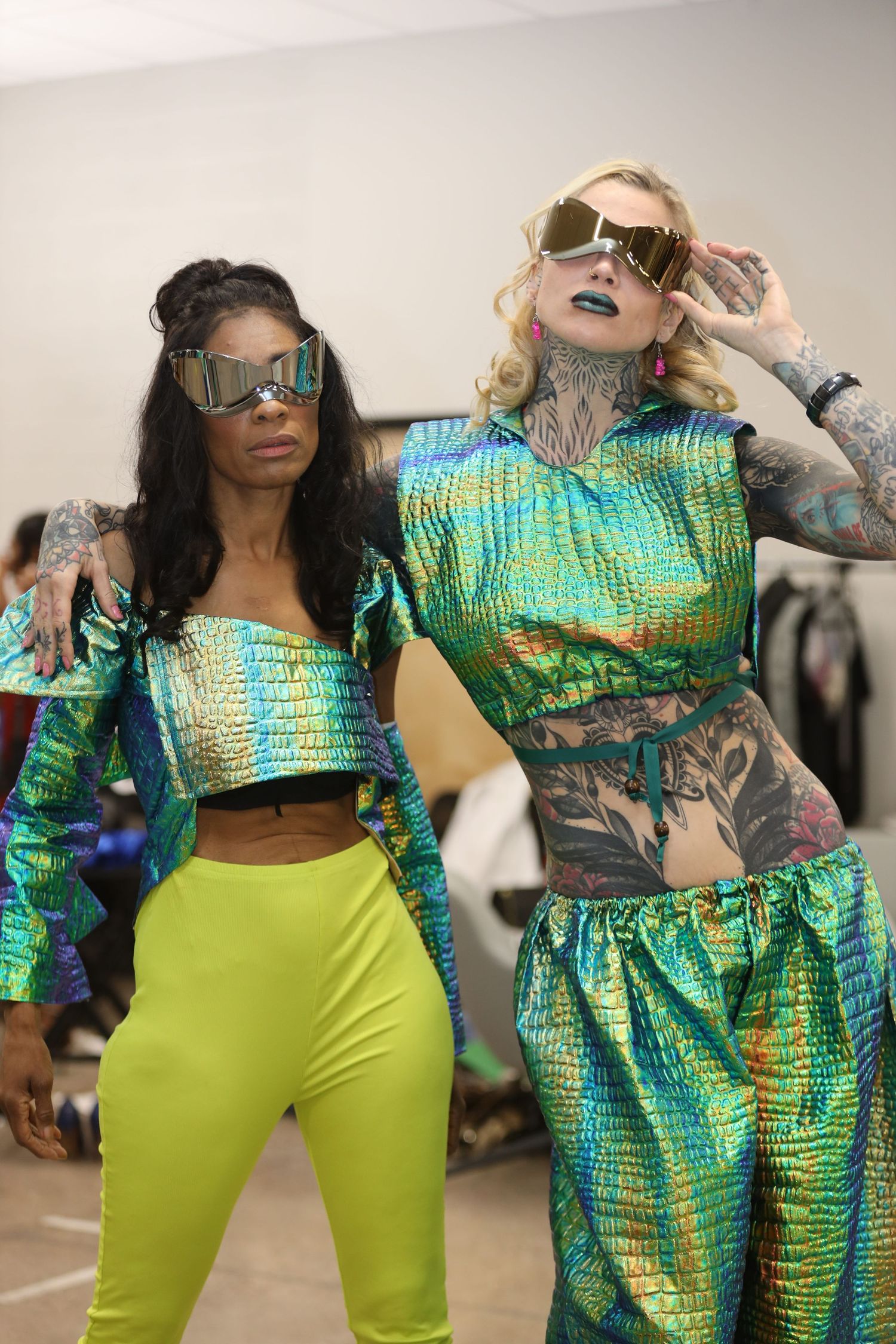 Models showcase vibrant green and metallic cropped outfits in a fashion presentation.