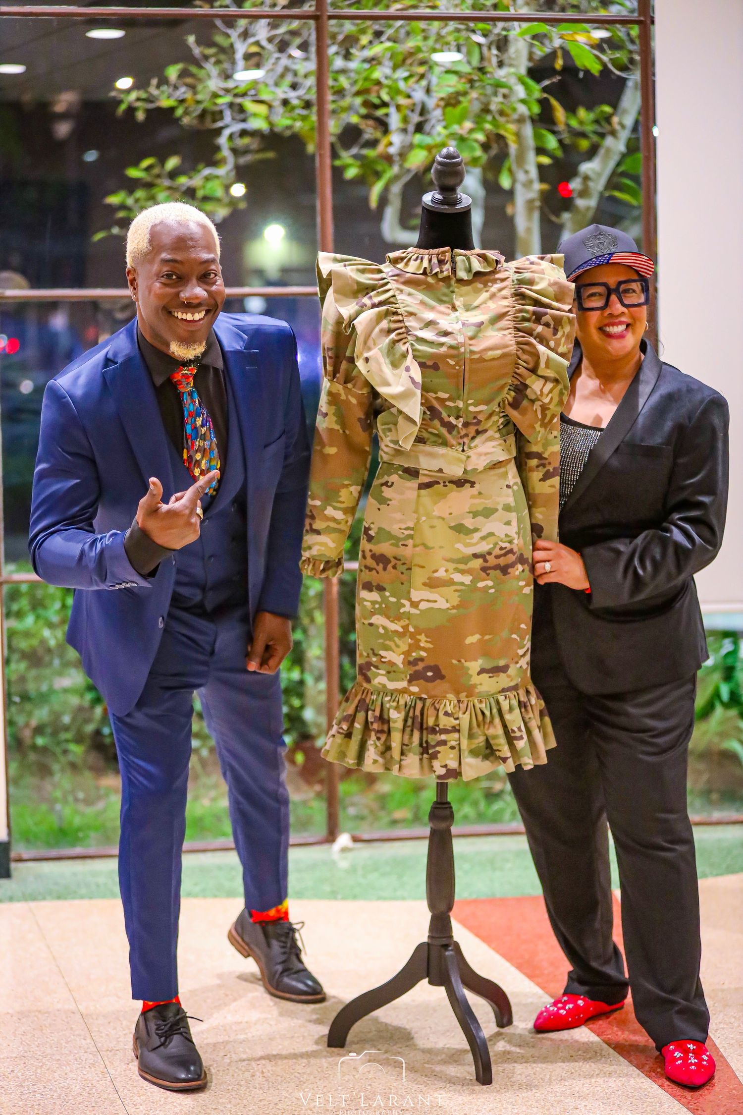 Display of military-style uniforms on mannequins with people posing alongside them.