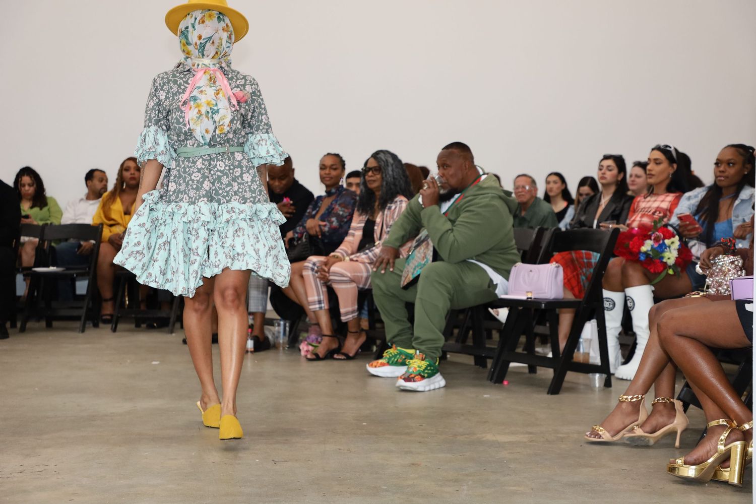 Models showcase outfits on a minimalist runway with seated audience members.