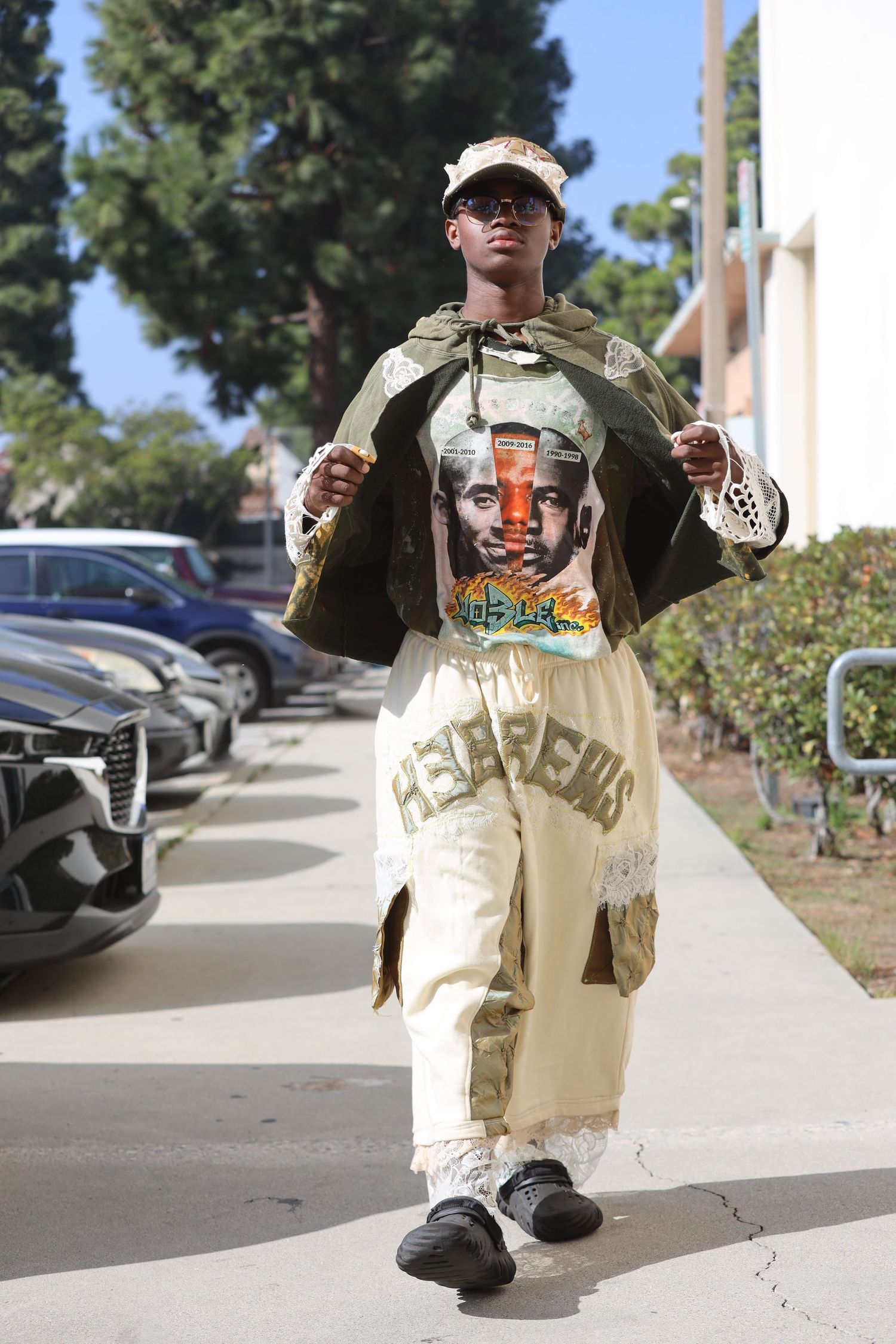 Person models urban streetwear outfit with graphic t-shirt and baggy pants on sidewalk.