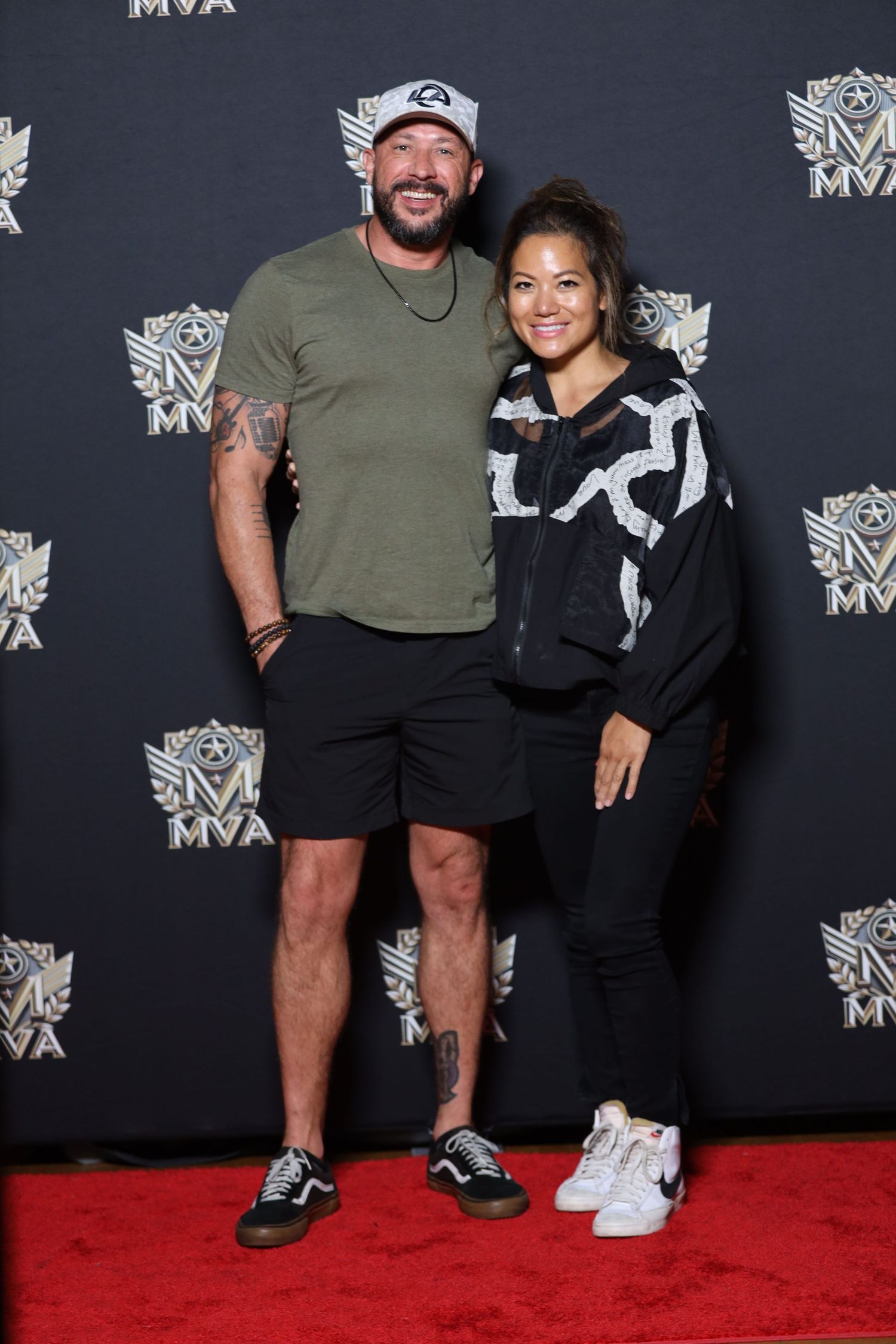 Two people smile for a photo against a dark backdrop with MVA logos at a formal event.