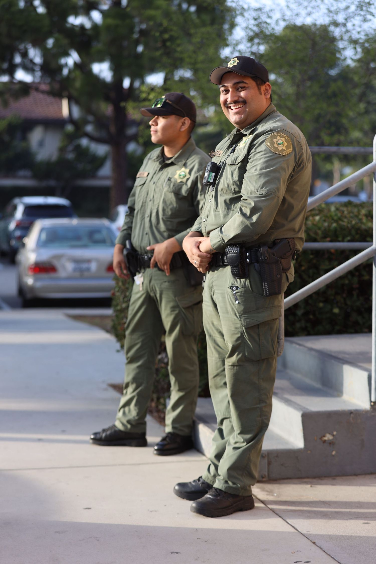 Law enforcement officers in olive green uniforms stand outside a building.