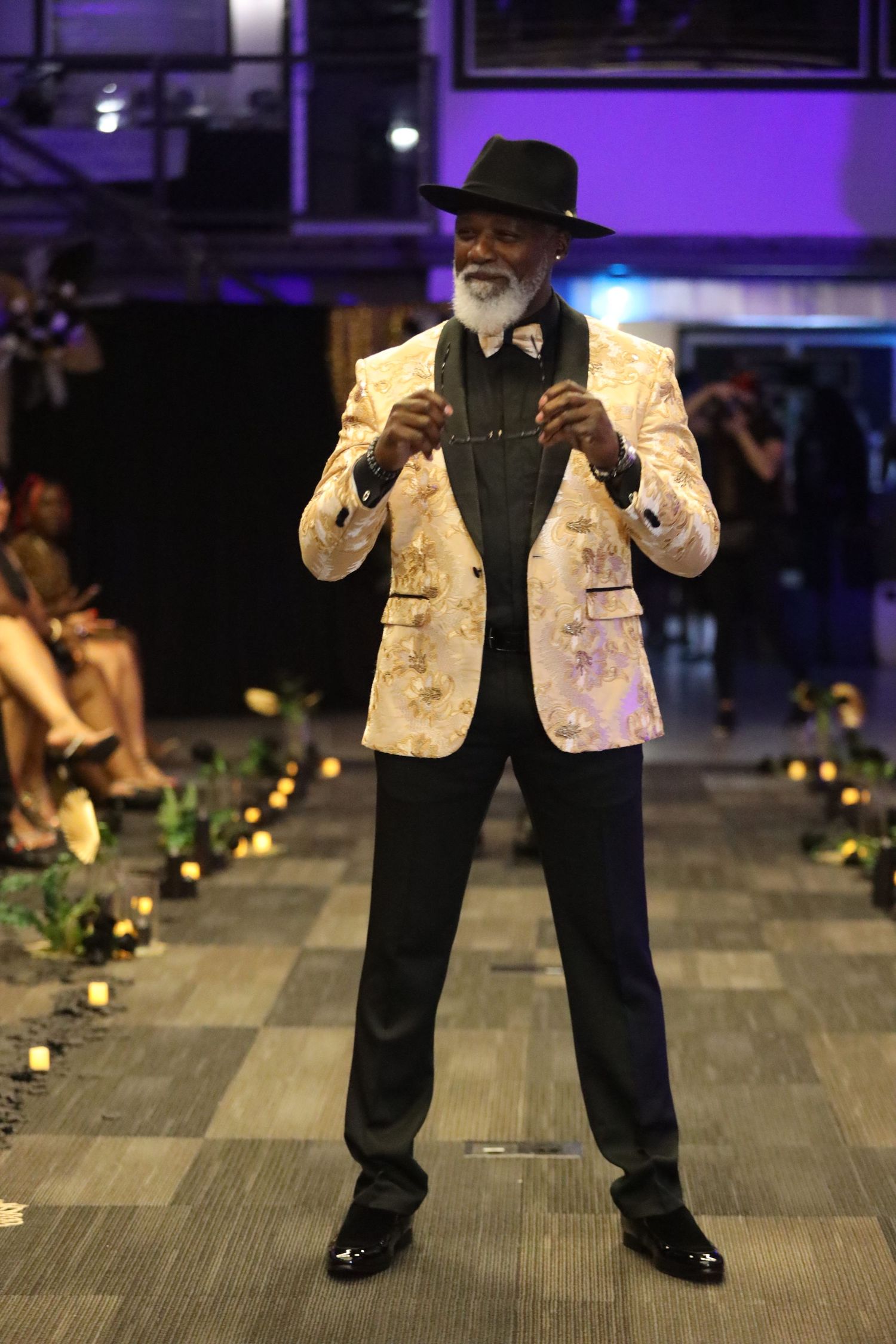 Cream sequined vest with black pants ensemble shown on illuminated runway.