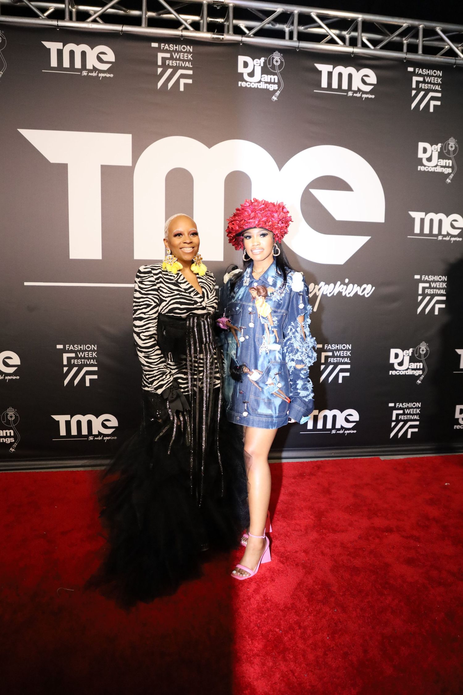 Fashion event attendees pose in avant-garde outfits against TME backdrop.