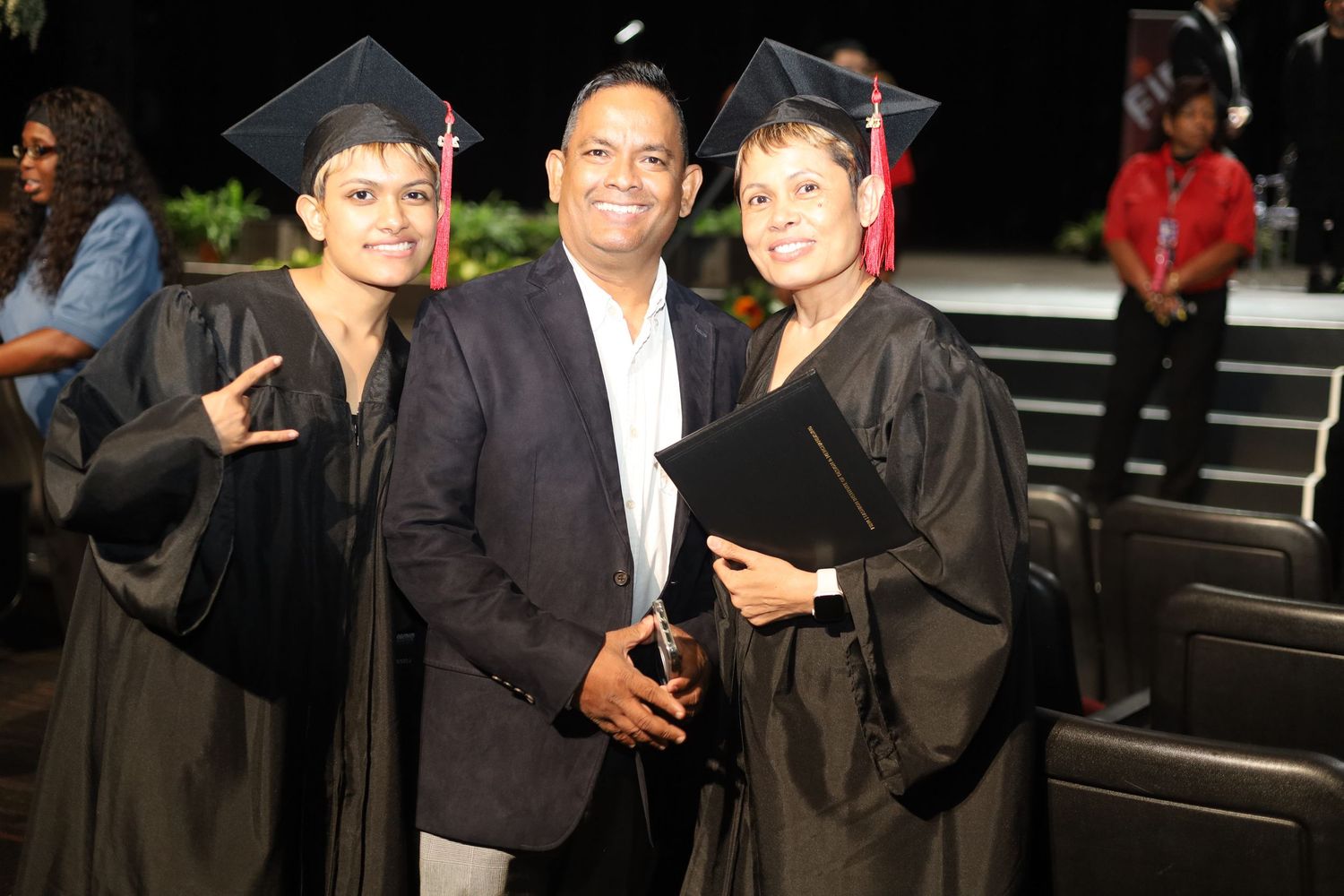 Group of graduates posing together in black graduation gowns.
