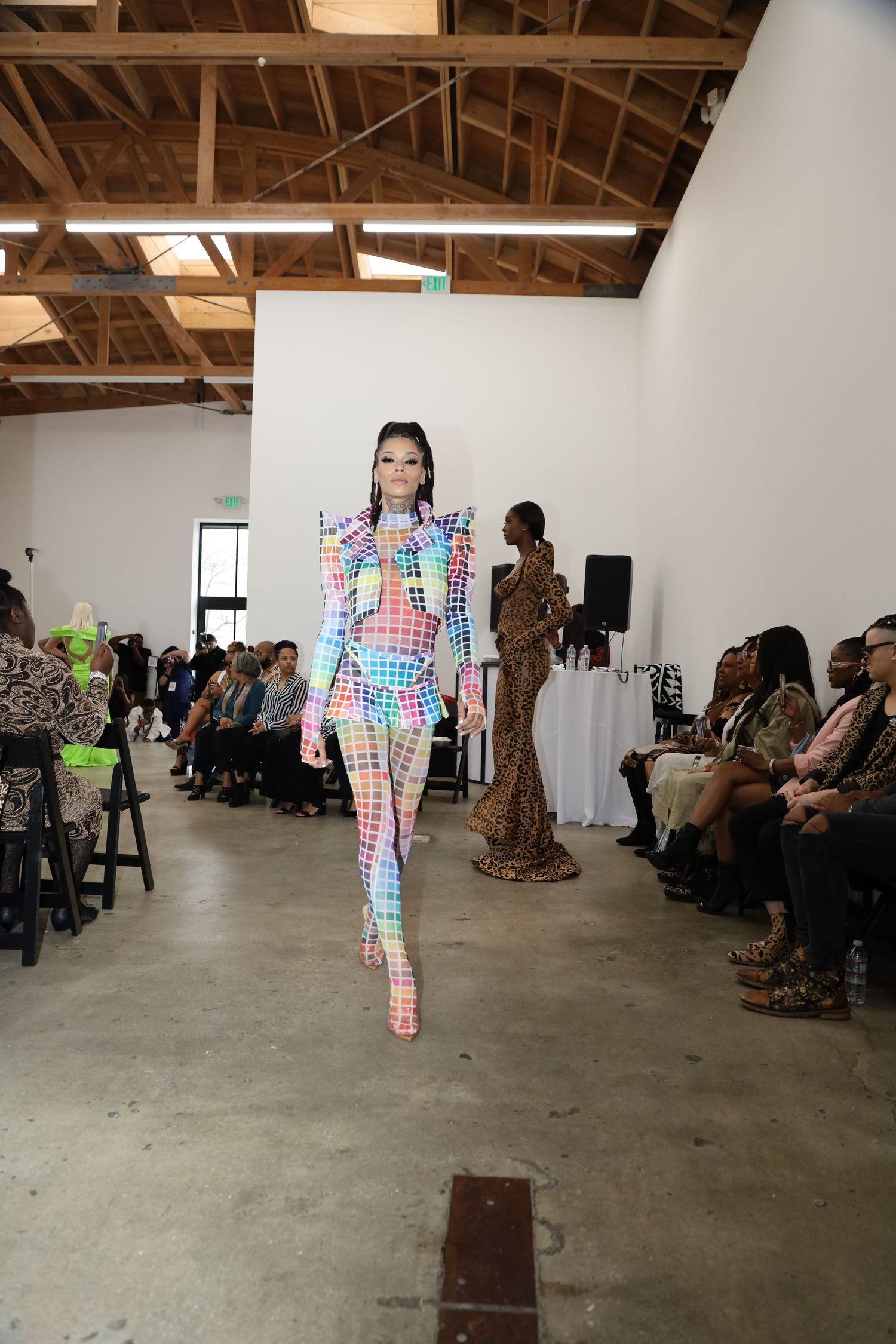 A runway model walks in a colorful geometric print catsuit at a fashion show.
