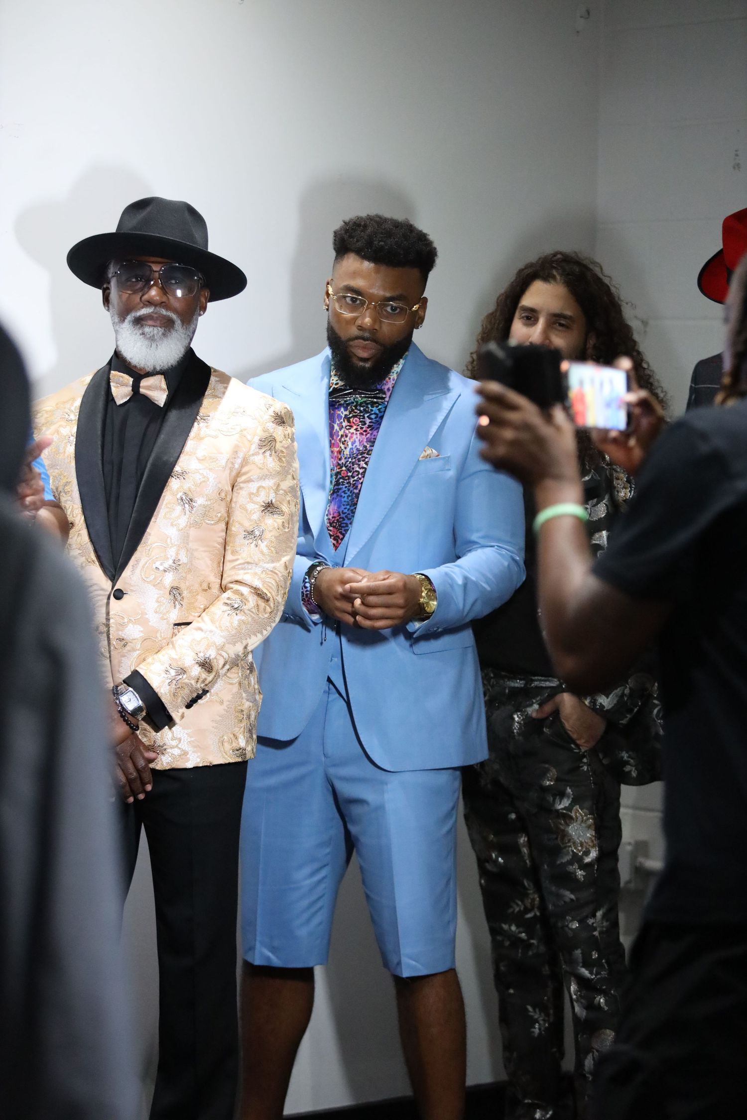 Group in formal attire including light blue and floral suits posing at social event.