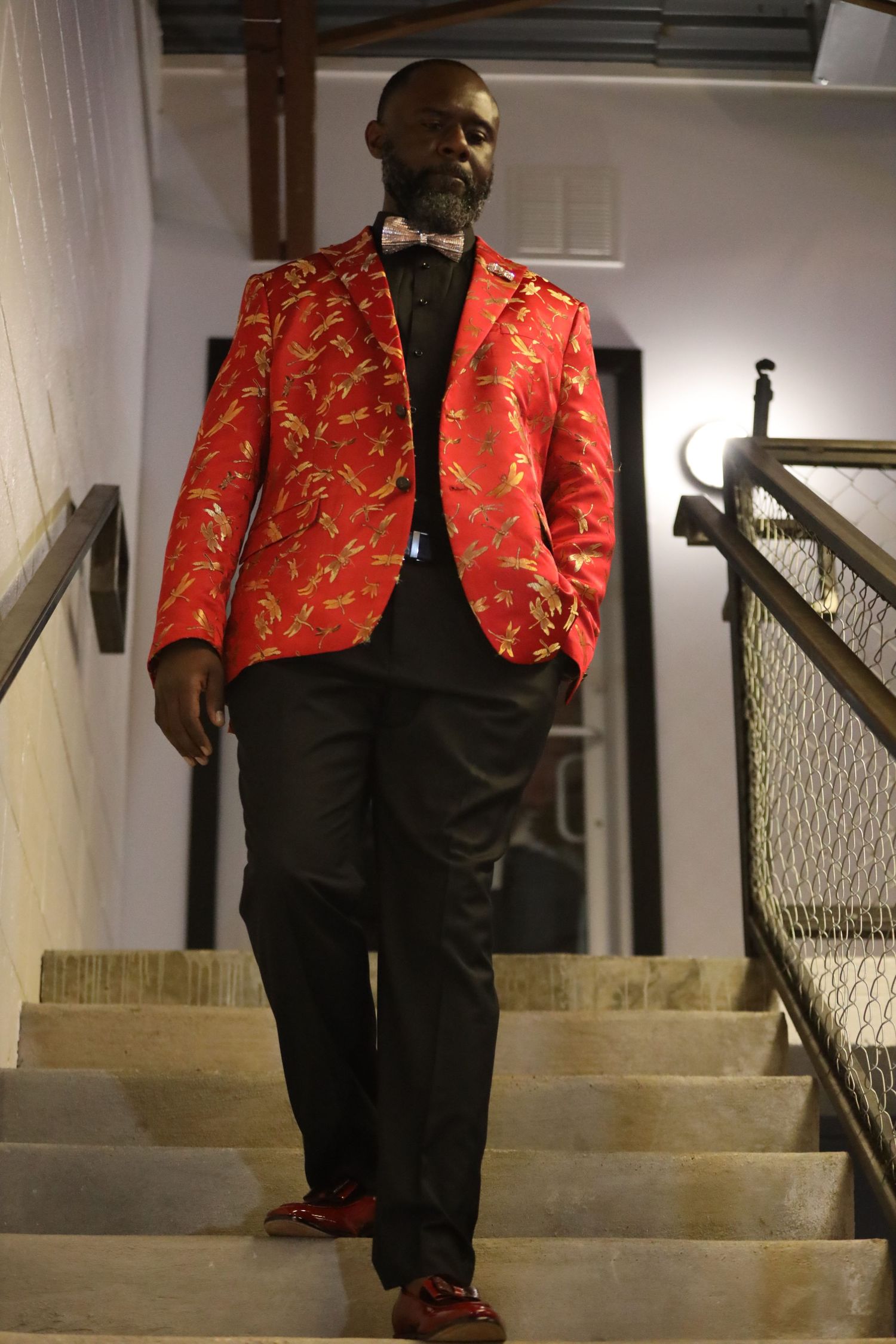 Person wearing red patterned jacket descending concrete stairs.