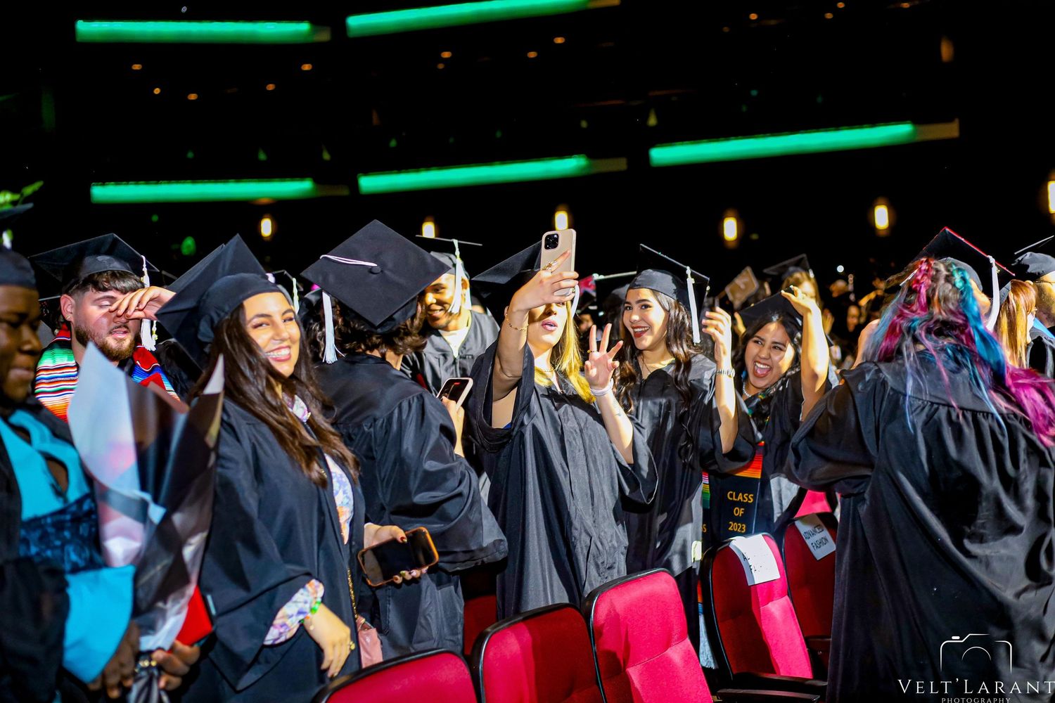 Graduates in black caps and gowns celebrating during graduation ceremony.