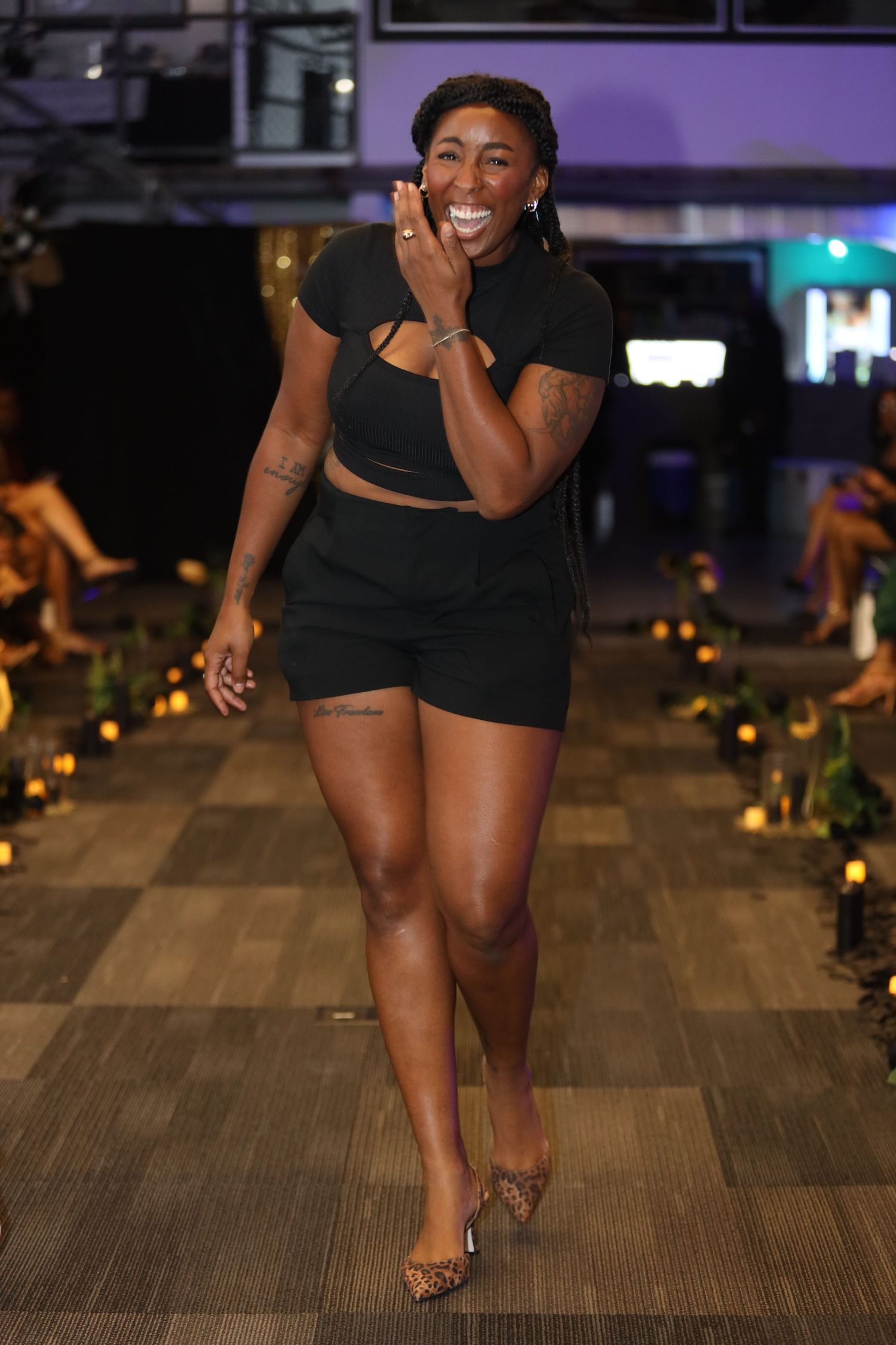 Person in black outfit dancing on wooden floor with ambient lighting.