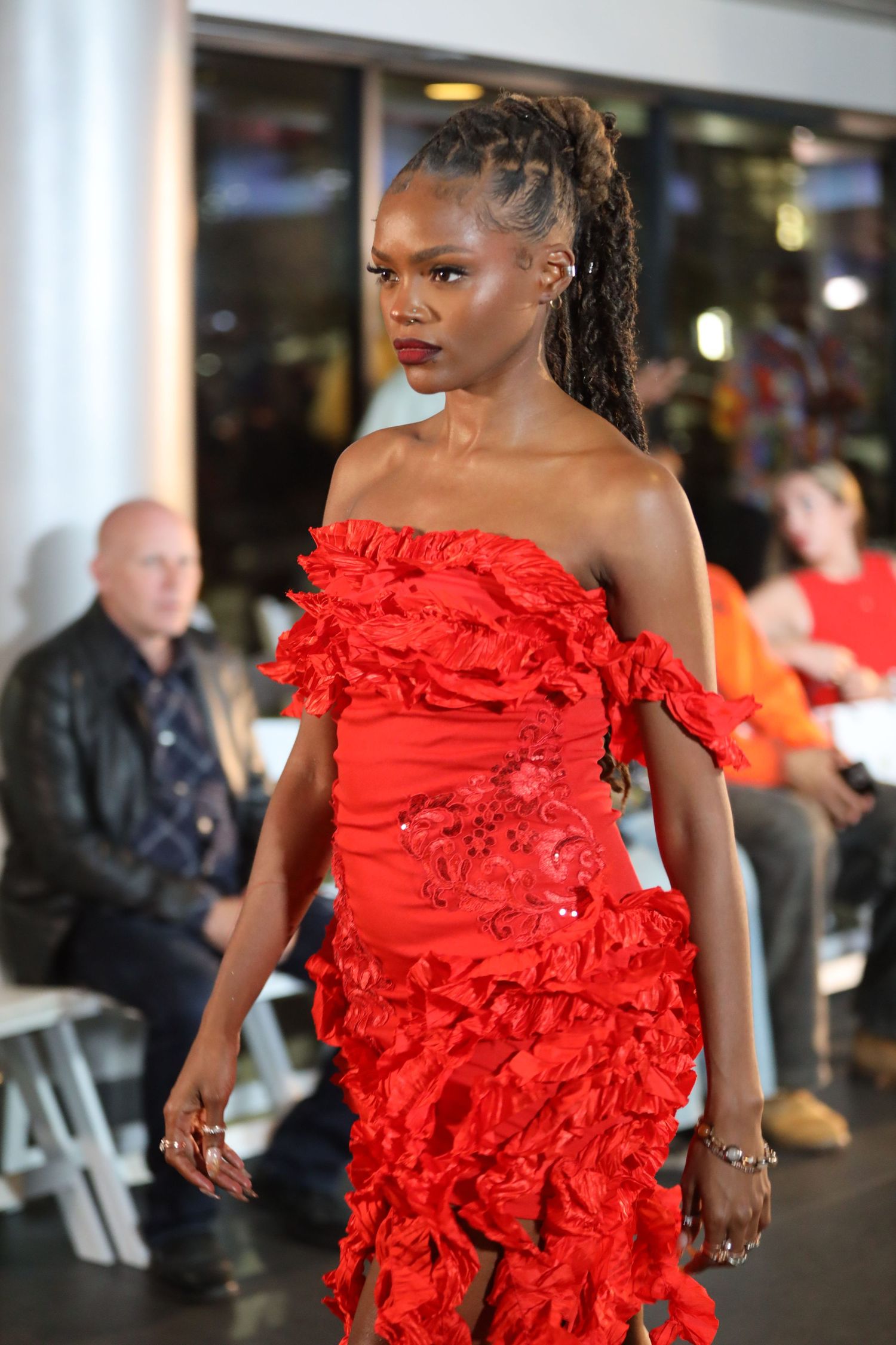 Stunning red ruffled gown with asymmetrical design displayed on catwalk.