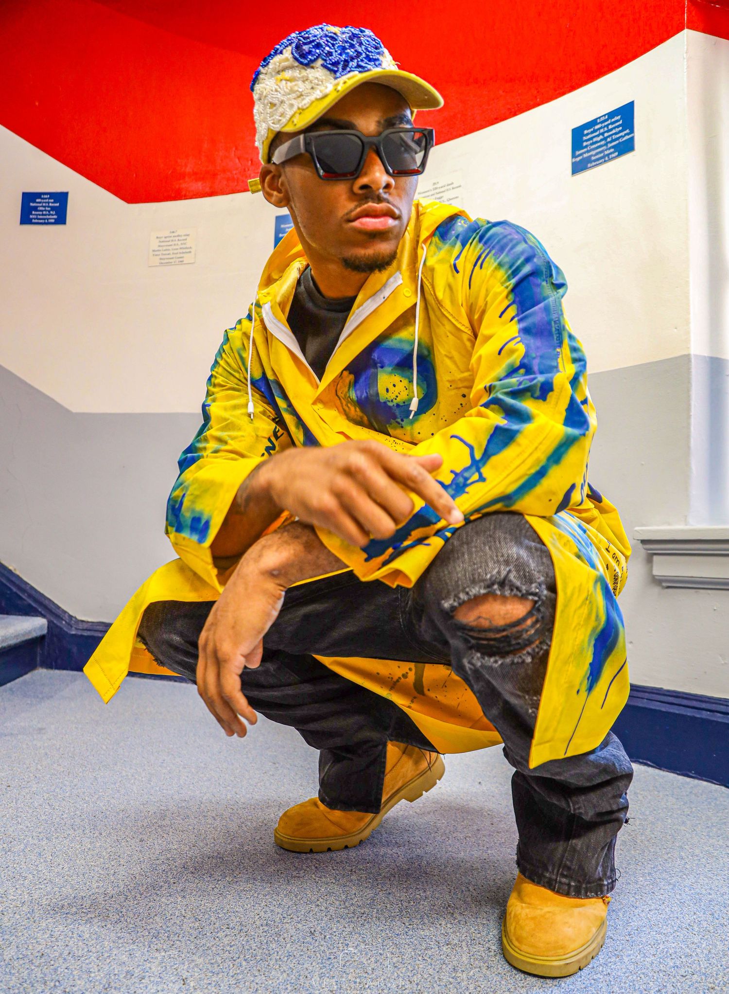 Person in yellow and blue tracksuit crouches on blue floor in dynamic pose.