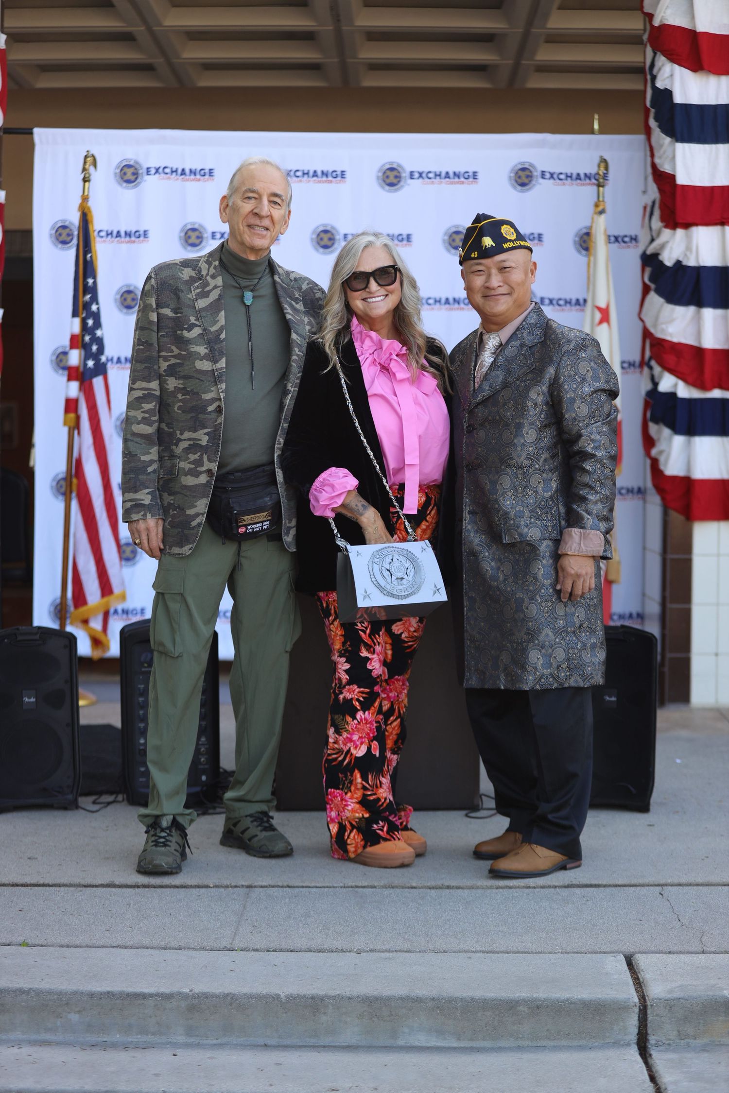 Veterans posing together at a formal event with American flags in the background.