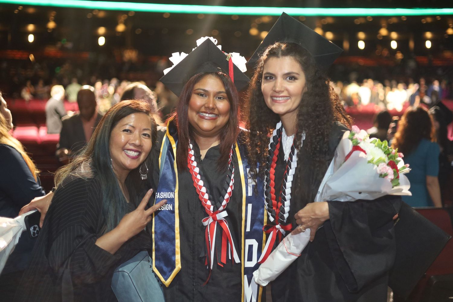 Graduates wearing colorful stoles and cords celebrate at commencement.