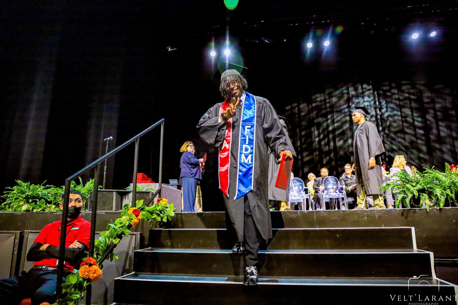 Wide view of graduation ceremony stage with decorative banners and lighting.