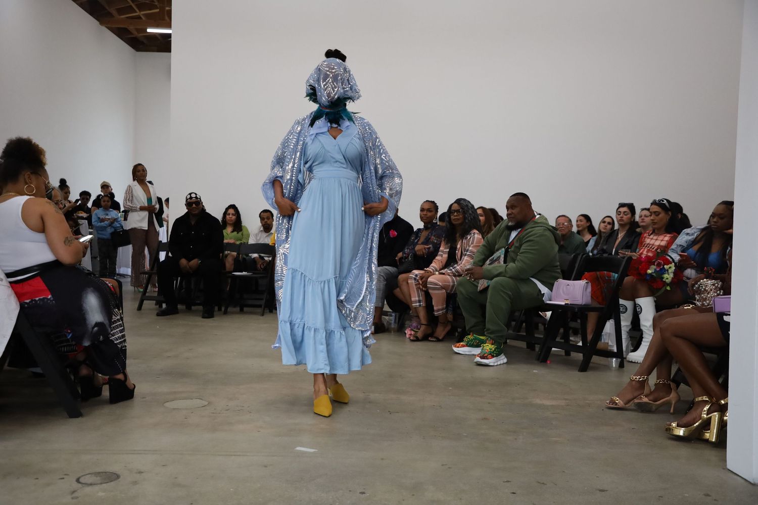Fashion presentation in an industrial space with models wearing pastel colored garments.