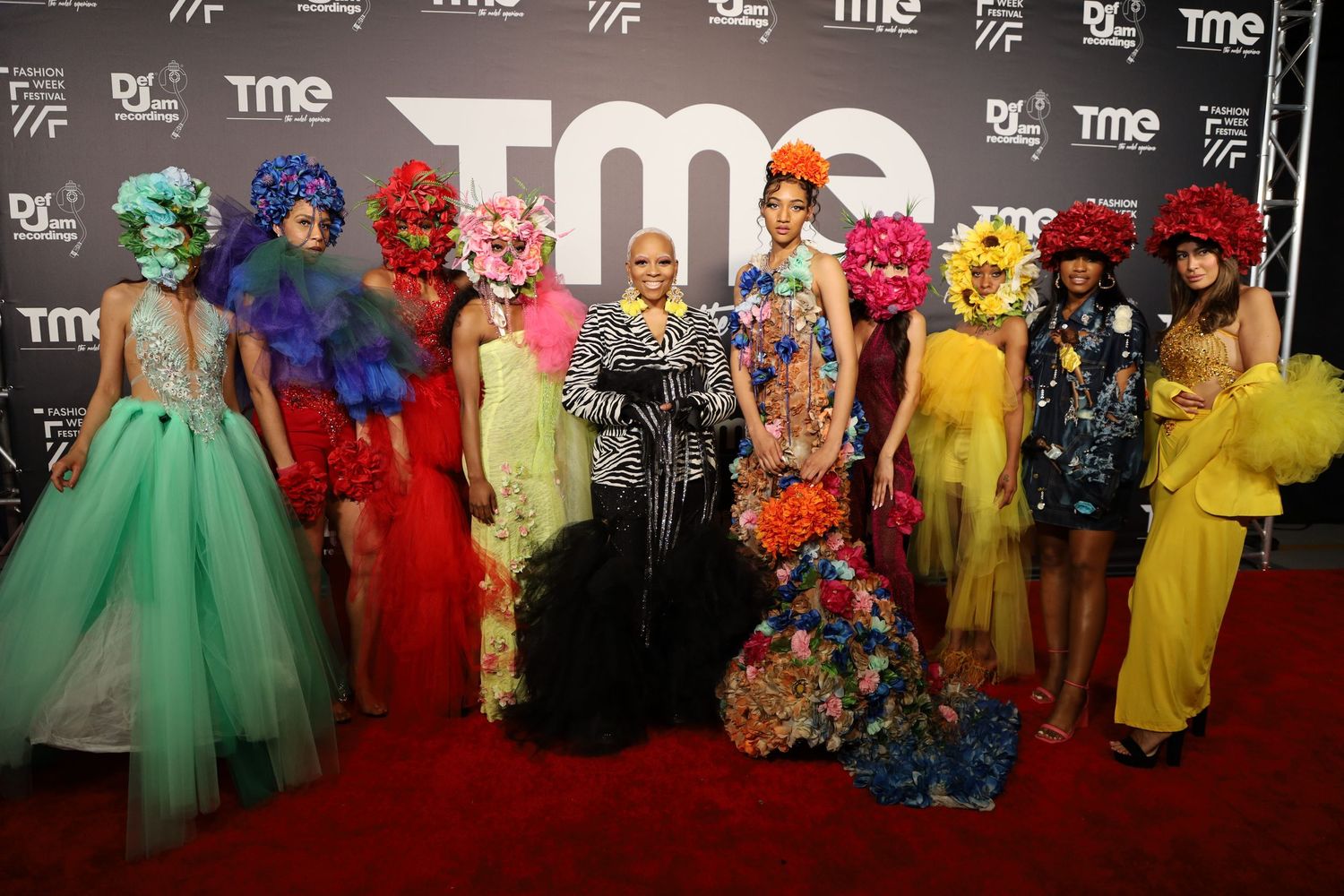 Red carpet group photo with attendees wearing bold colors at TME event.