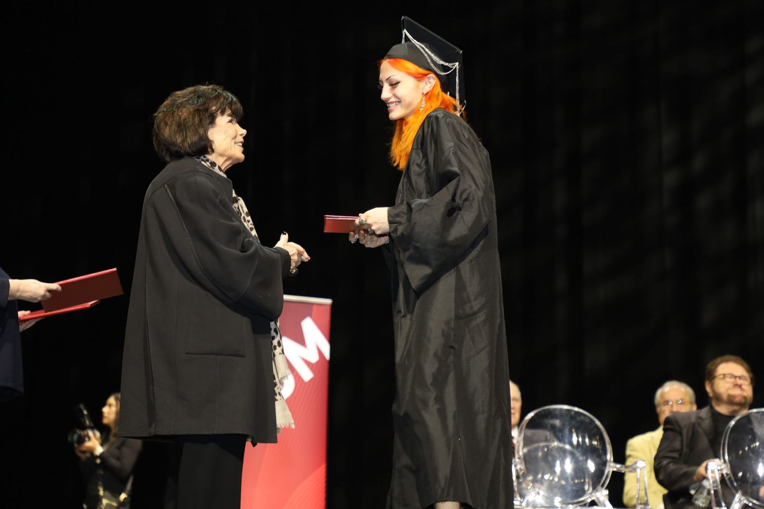 Graduate receives diploma holder during formal commencement ceremony.