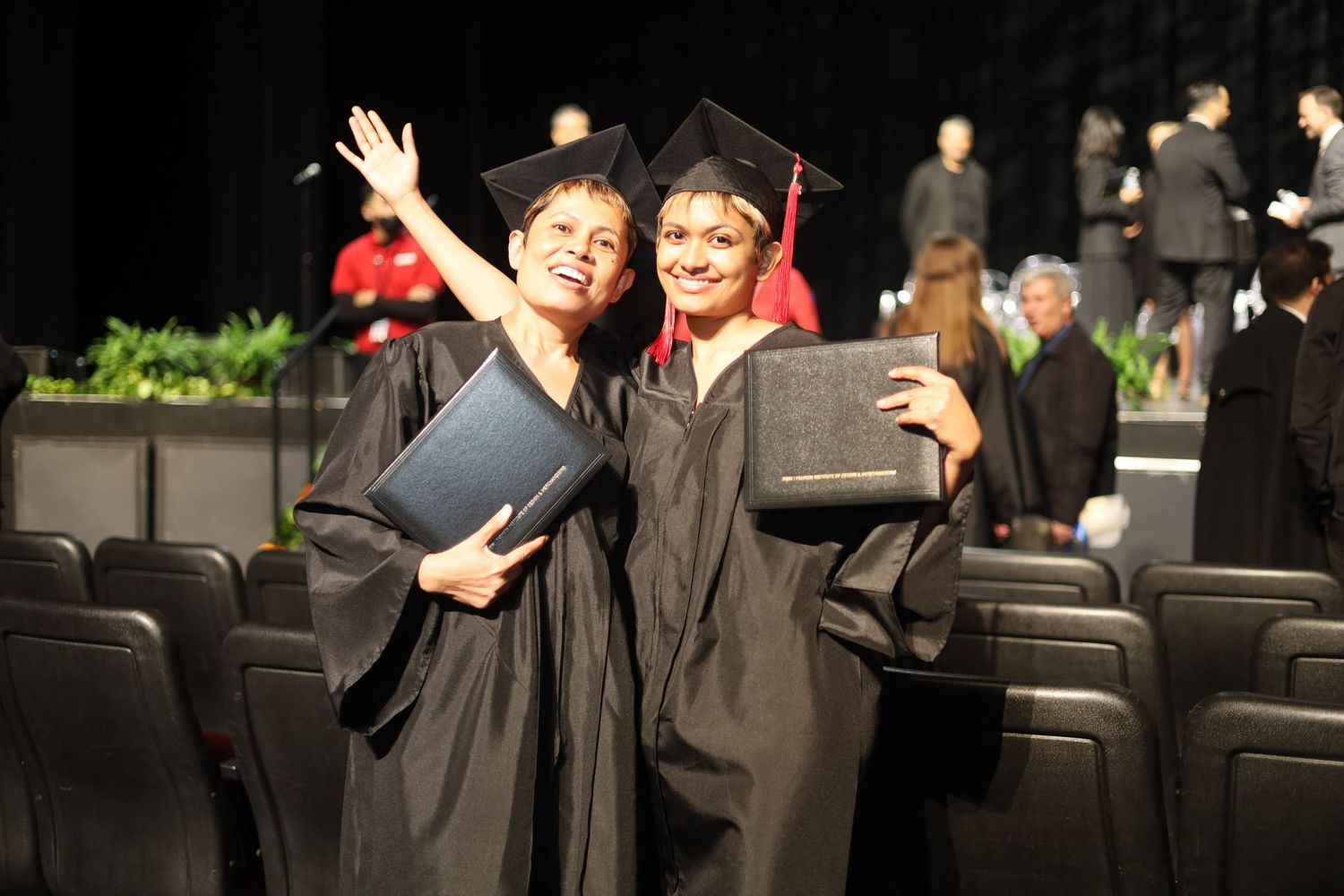 Graduates celebrate with raised arms during commencement ceremony.