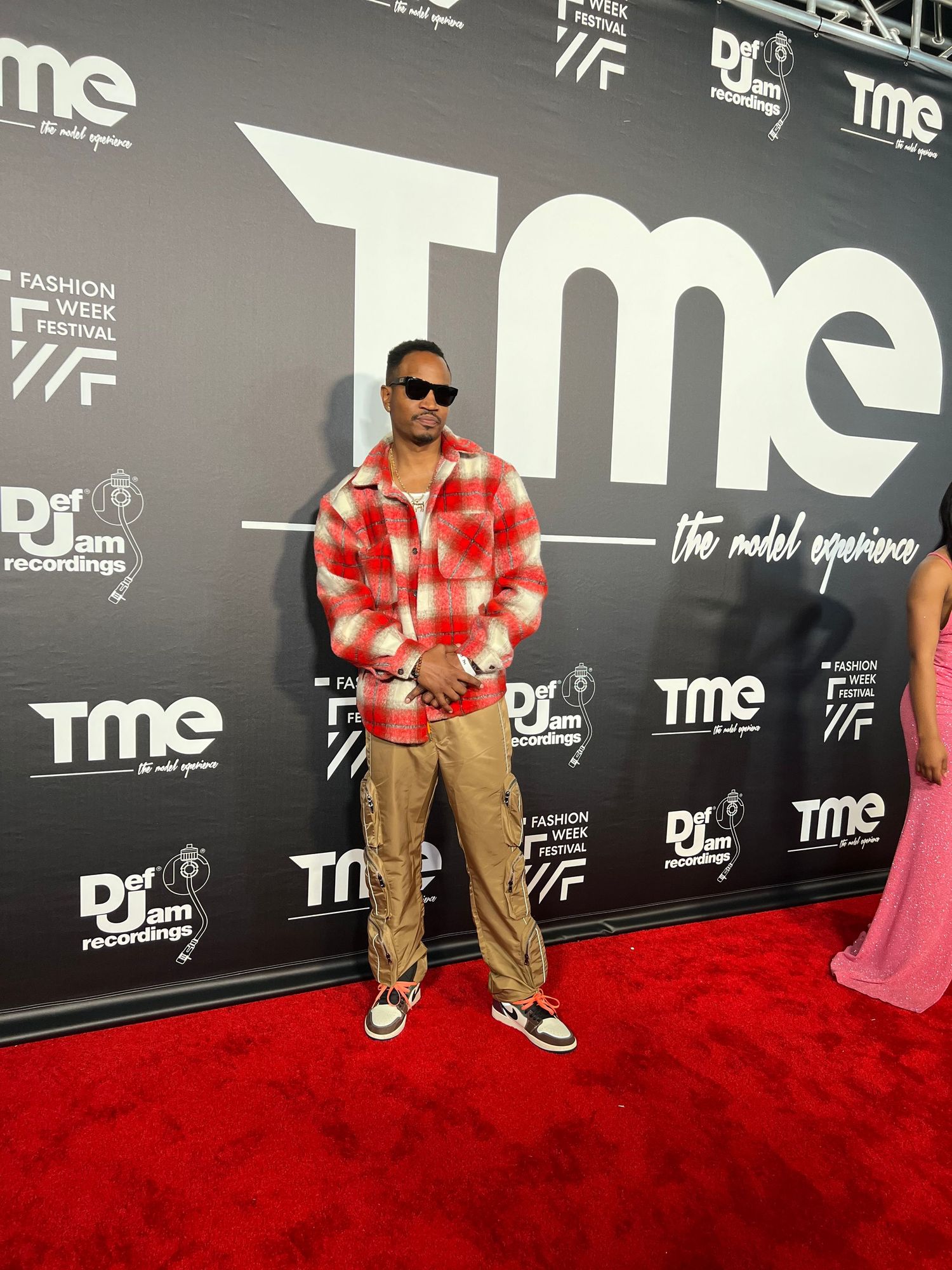 Red carpet photo showing attendee in casual khaki outfit against TME branded backdrop.