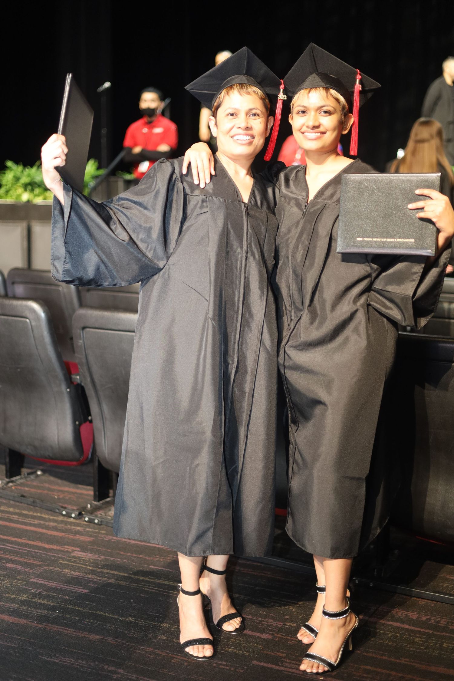 Graduates in traditional black regalia posing on wooden steps.
