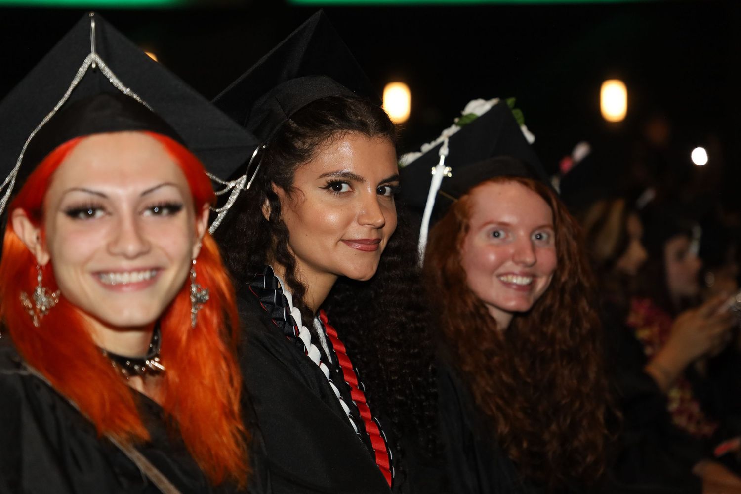 Students in graduation attire celebrate on stage during a commencement ceremony.