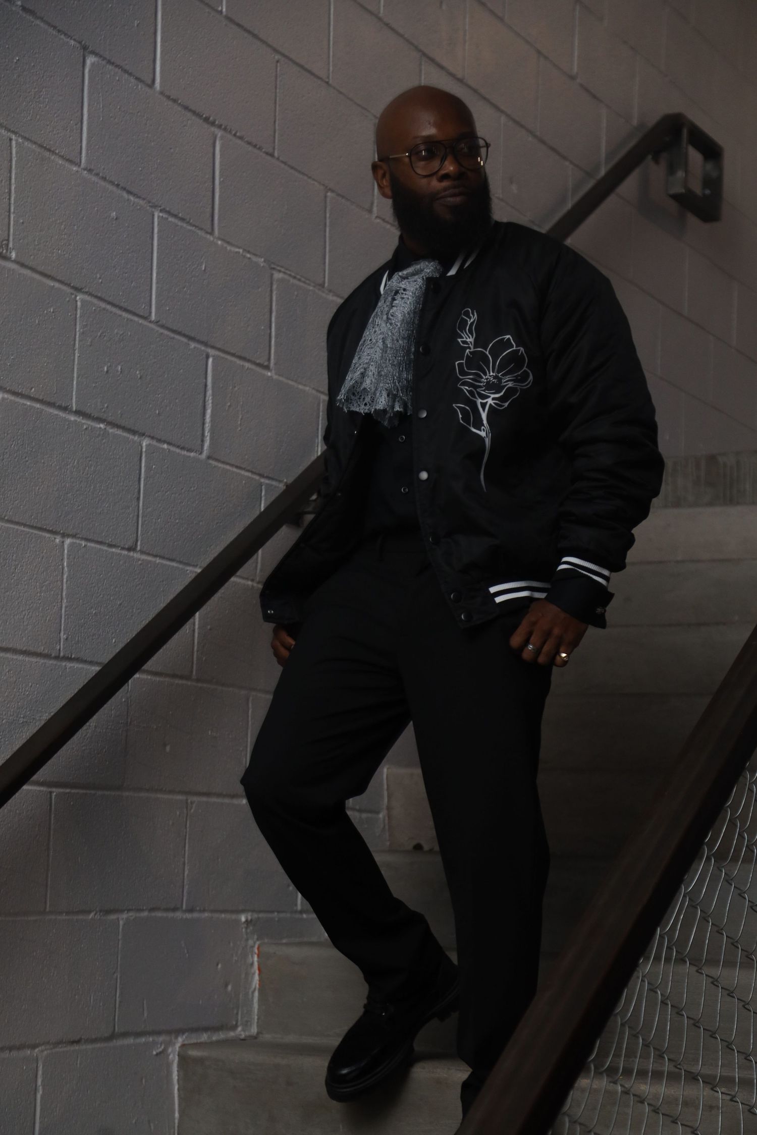 Person in dark clothing sitting on concrete stairs against white block wall.