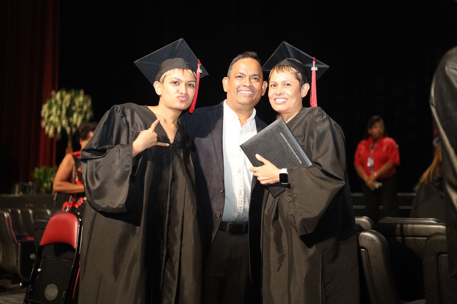 Three graduates in academic regalia celebrate their achievement.