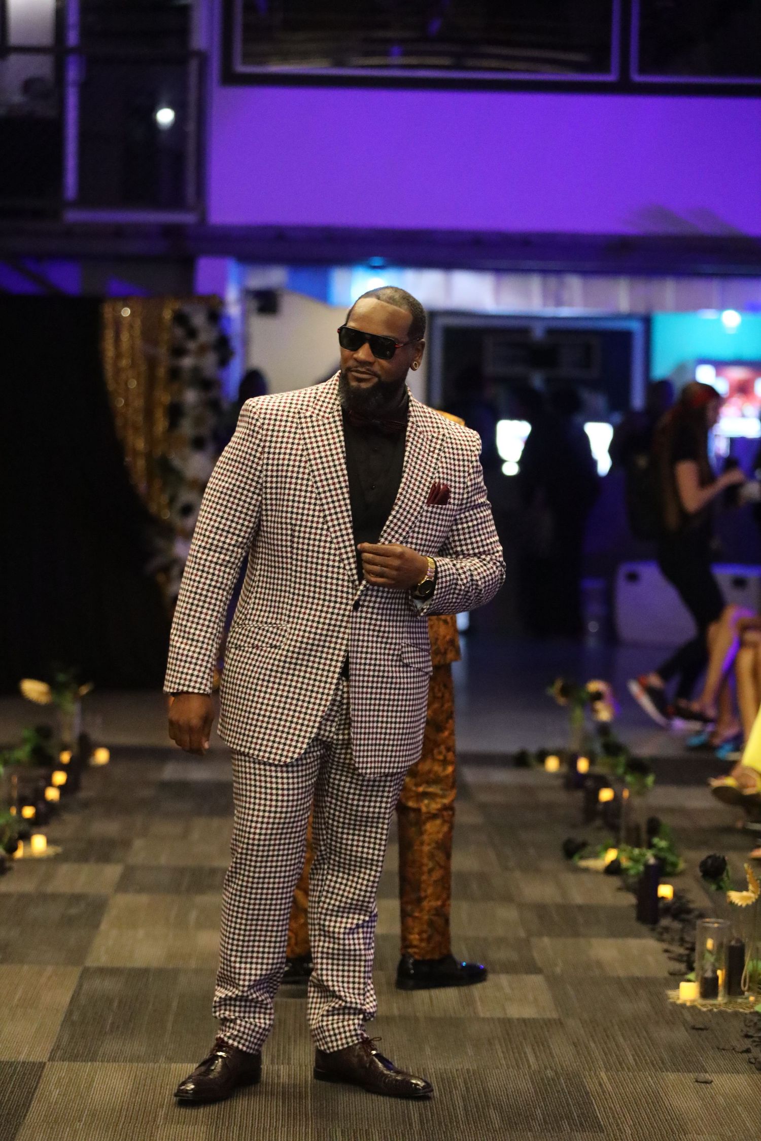 White and black houndstooth suit displayed on fashion runway with ambient lighting.