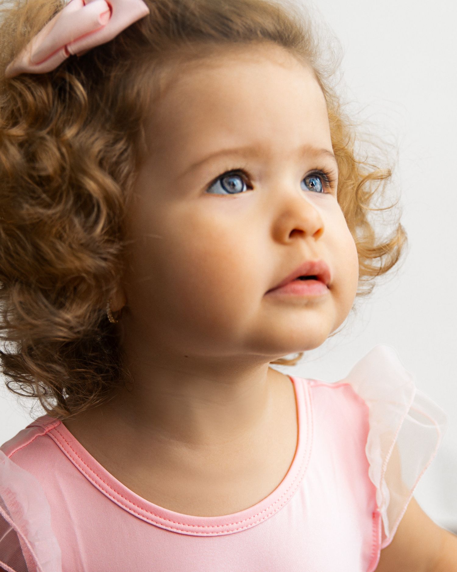 A series of close-up portraits showing a child with curly hair and rosy cheeks wearing a pink shirt.