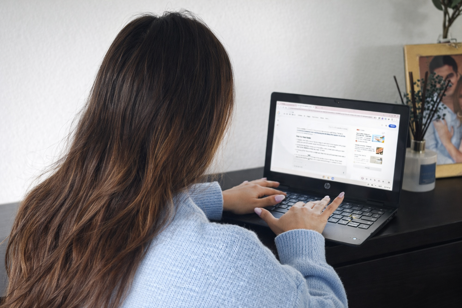 Student working at desk with laptop and papers while studying in a home office environment.