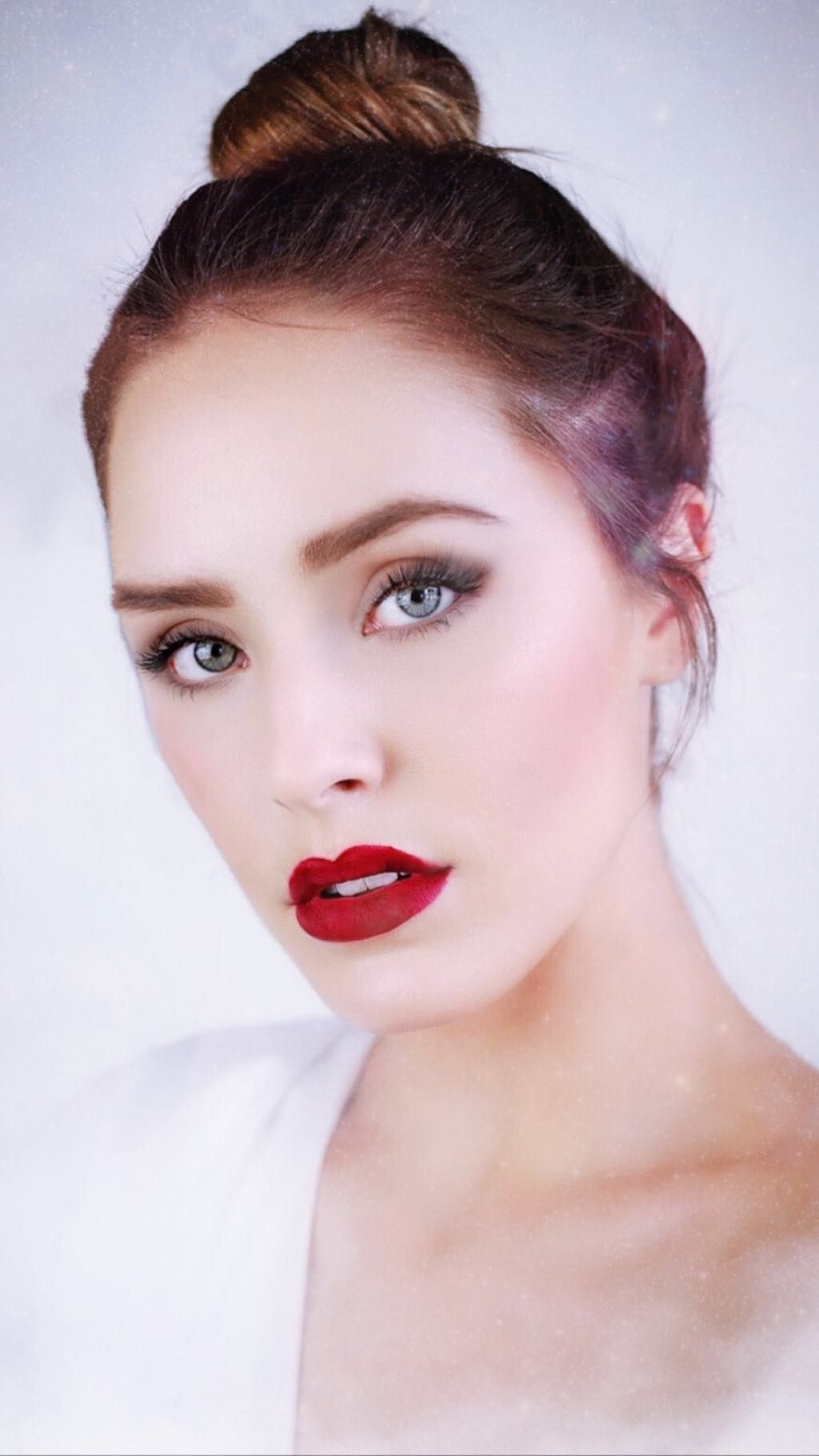Beauty portrait with classic red lipstick, smokey eye makeup and elegant updo hairstyle against light background.