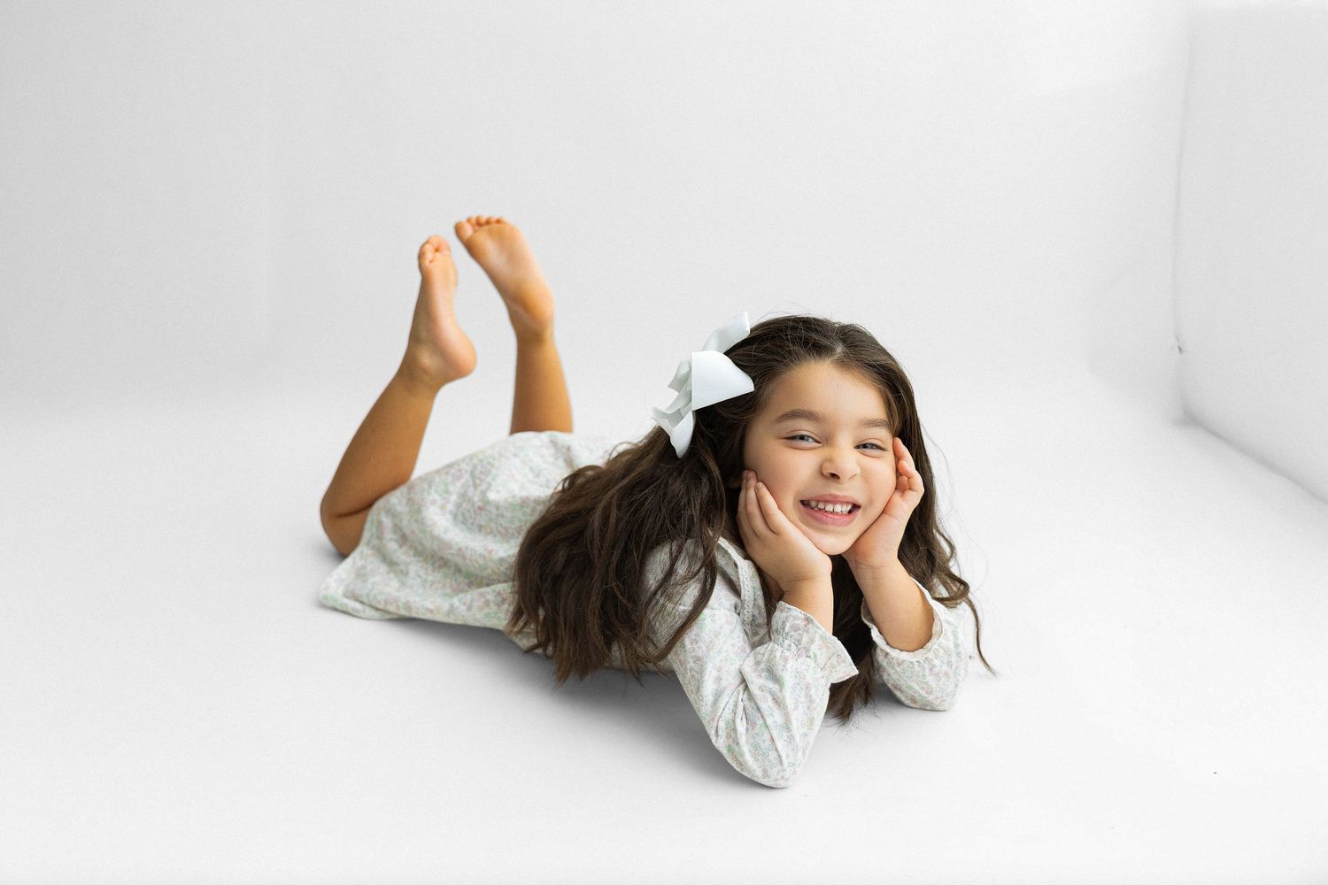 A person in a white outfit lies on a white background in four different dynamic poses.