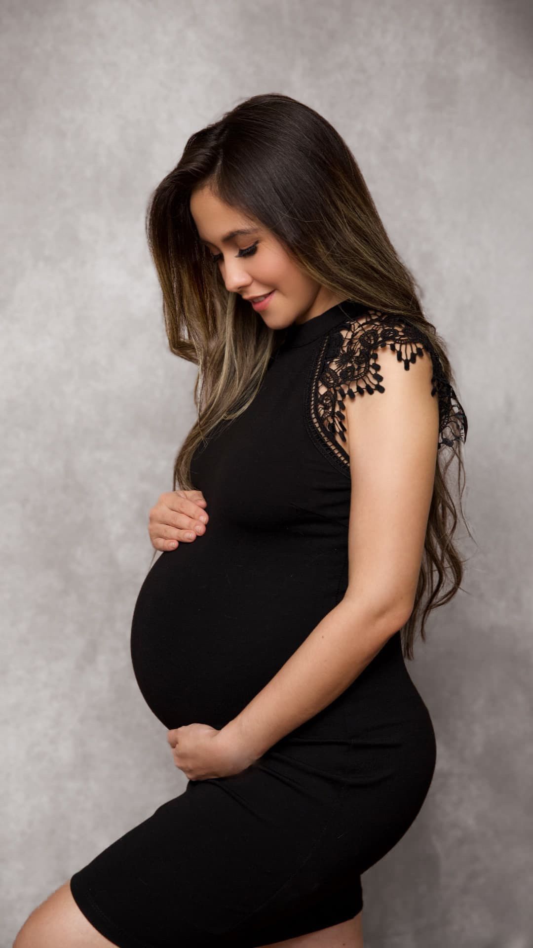 A maternity photo series showing a pregnant woman in a black dress against a gray backdrop in various poses.