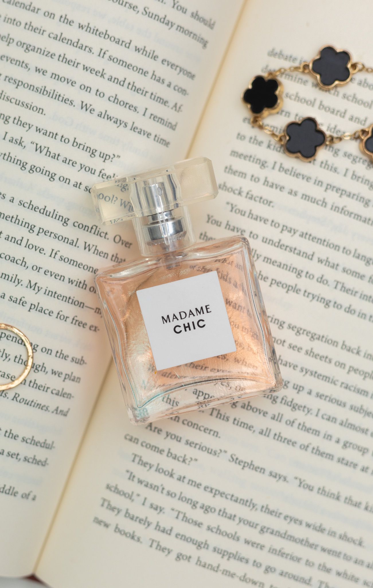 Perfume bottles rest elegantly on open book pages with text visible underneath in soft natural lighting.