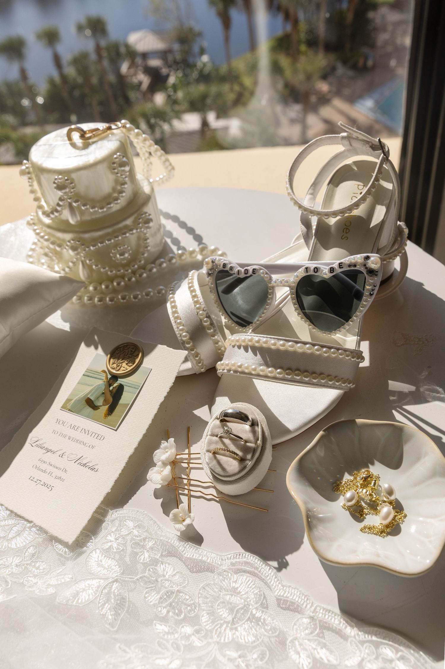 White pearl-embellished bridal sandals displayed in a row on a reflective surface with natural lighting.