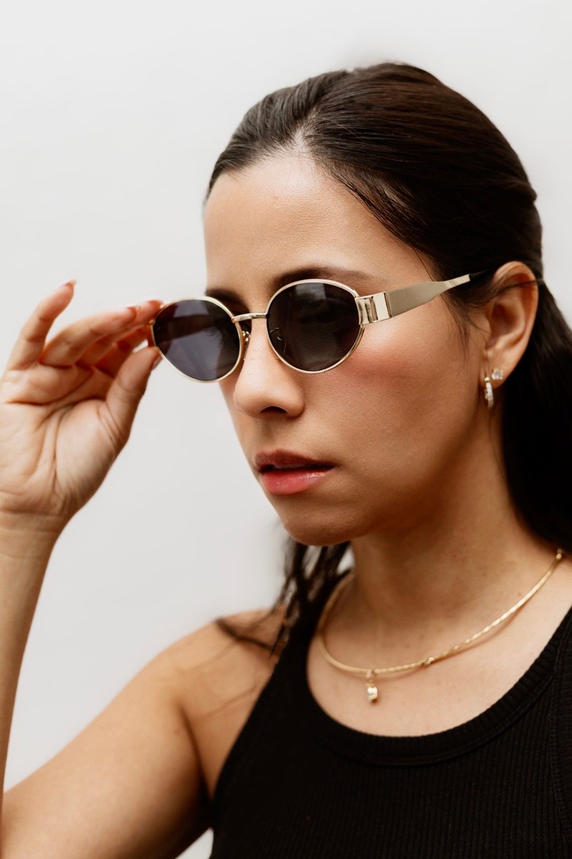 Person in black top modeling aviator sunglasses in a series of close-up shots against white background.