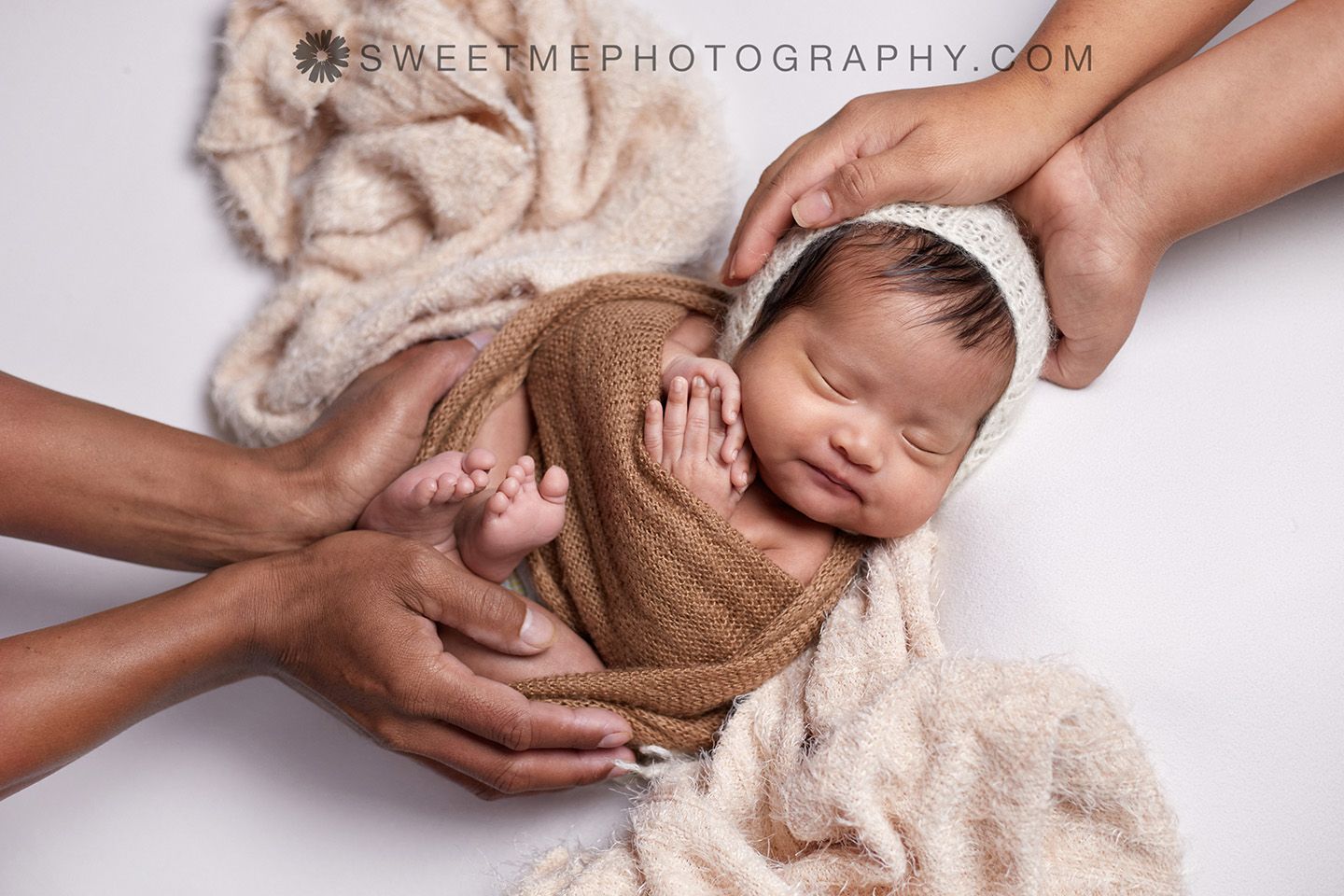 Close-up sequence of hands gently holding and positioning a sleeping newborn for a professional photo shoot.