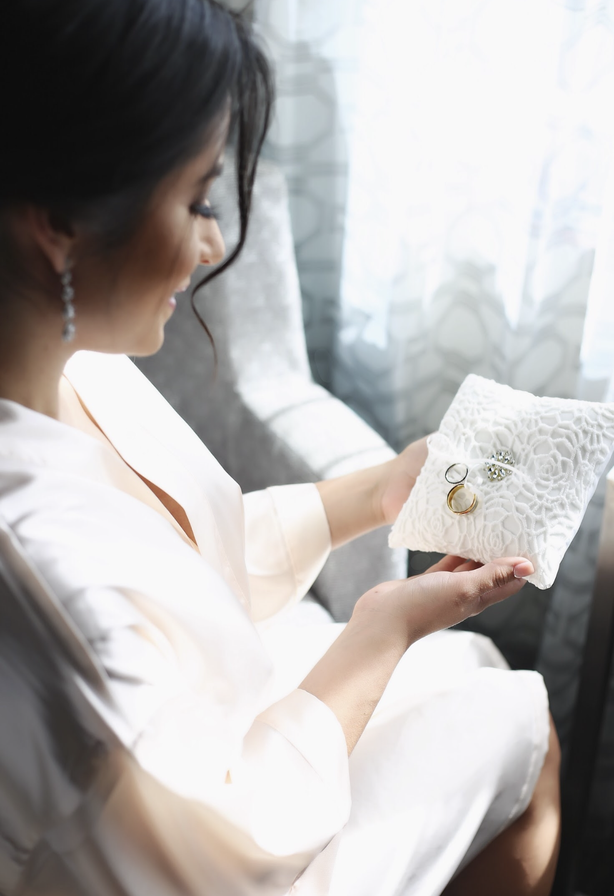 Bride in white robe reads a letter while getting ready on her wedding morning.