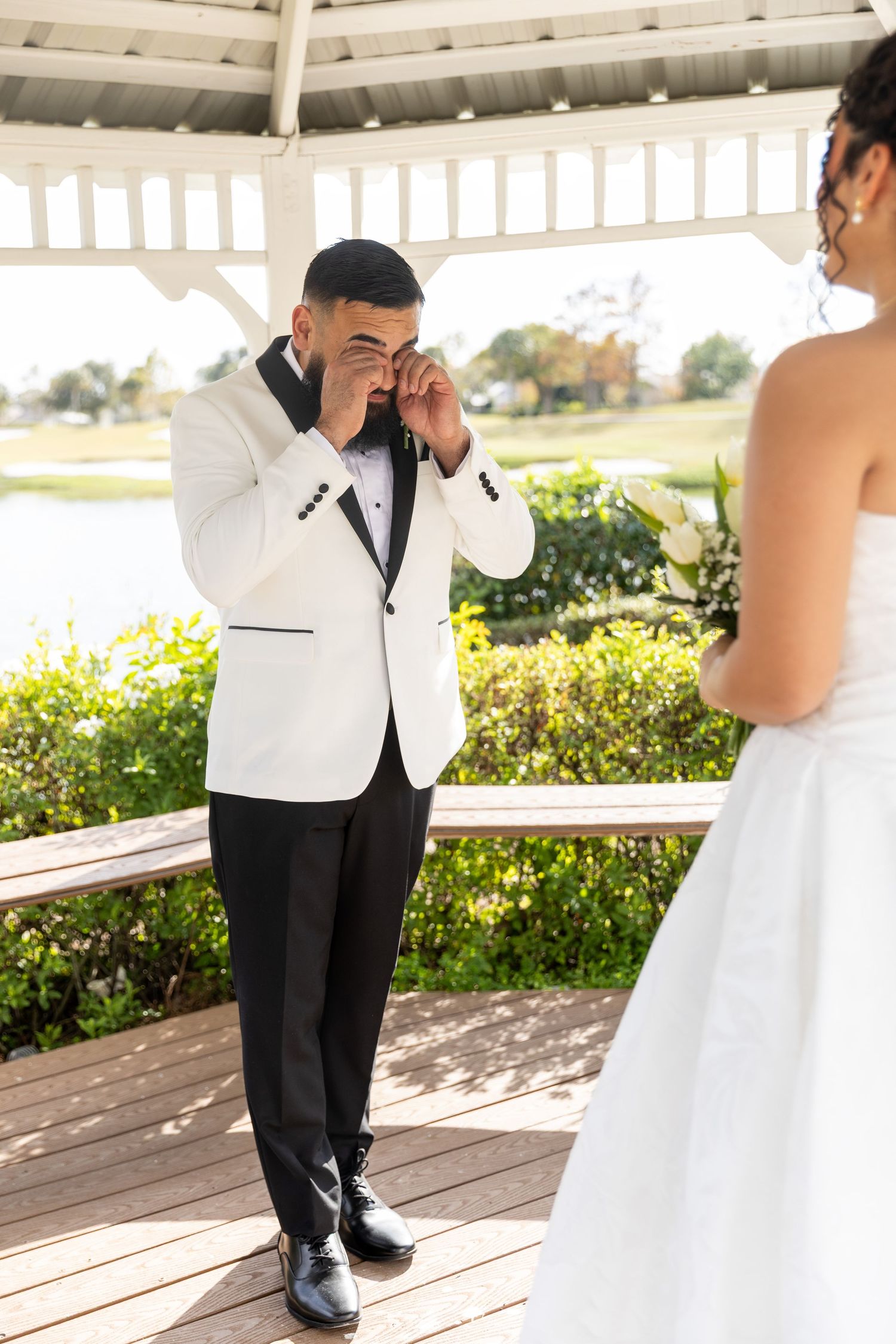Emotional first look moment between couple at outdoor gazebo during wedding ceremony.