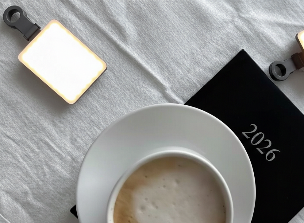 White ceramic coffee cup with frothy latte art sits on a light gray marble surface next to white sugar packets.