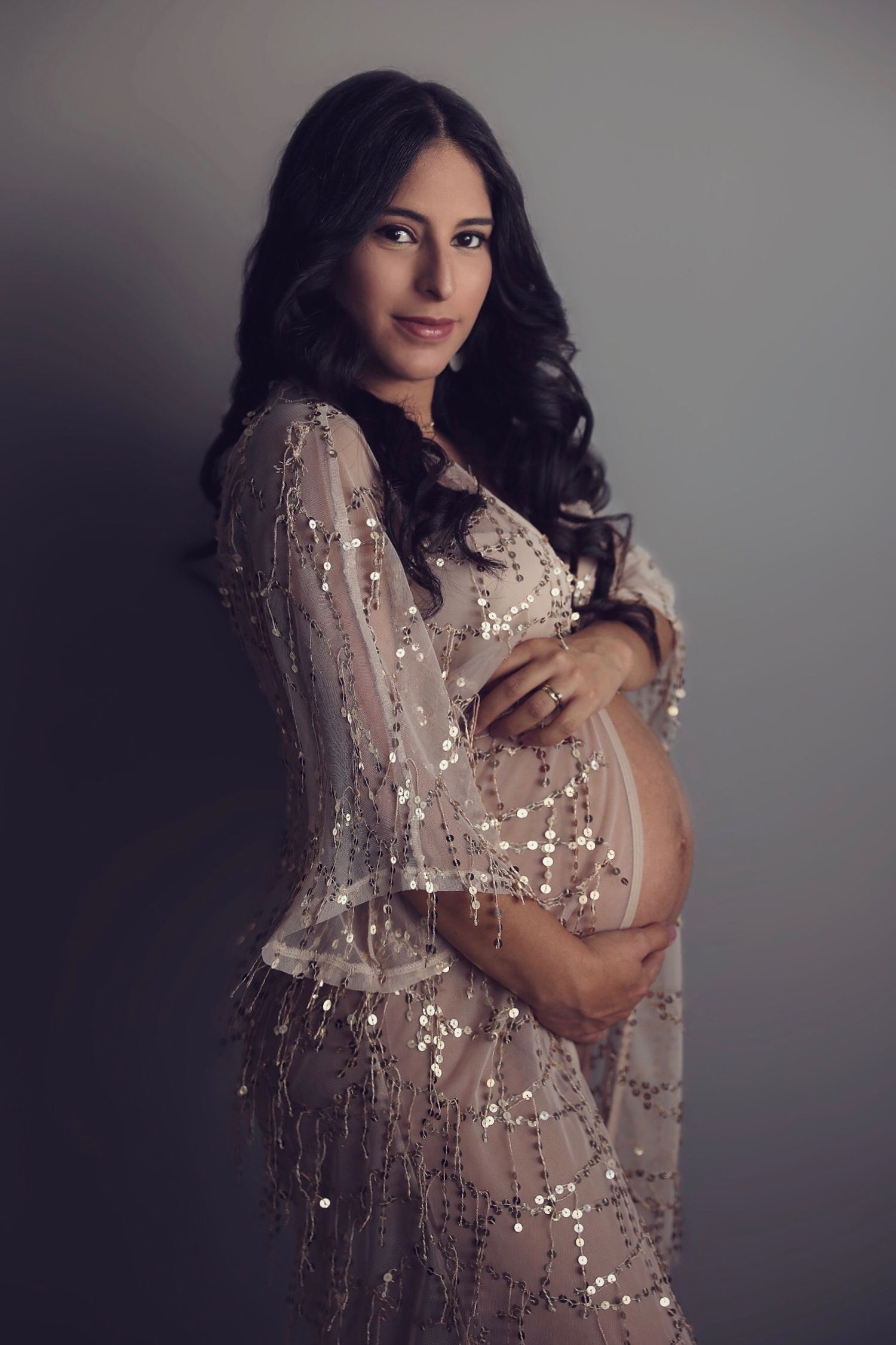 A glamorous fashion portrait featuring a sparkly beige sequined dress against a dark studio background.