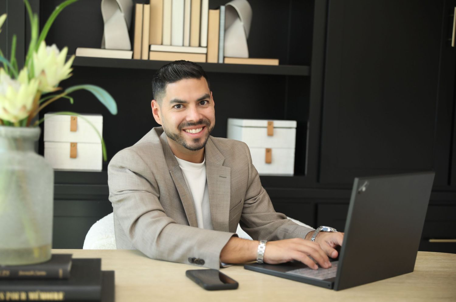 Professional working at modern desk setup with laptop and monitor in contemporary office environment.