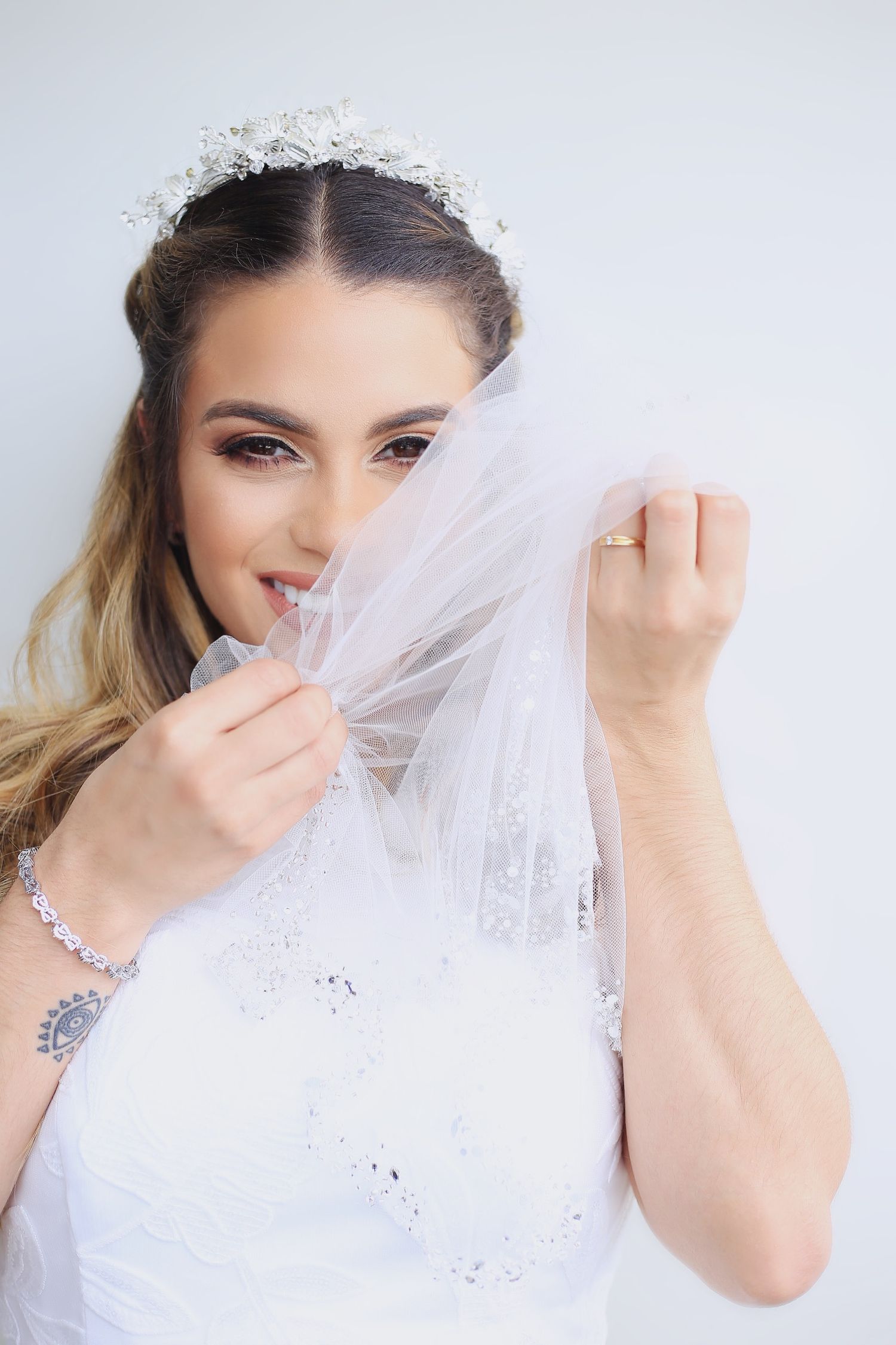 Ethereal bridal portraits showing delicate white veil details and sparkling jewelry against a light background.