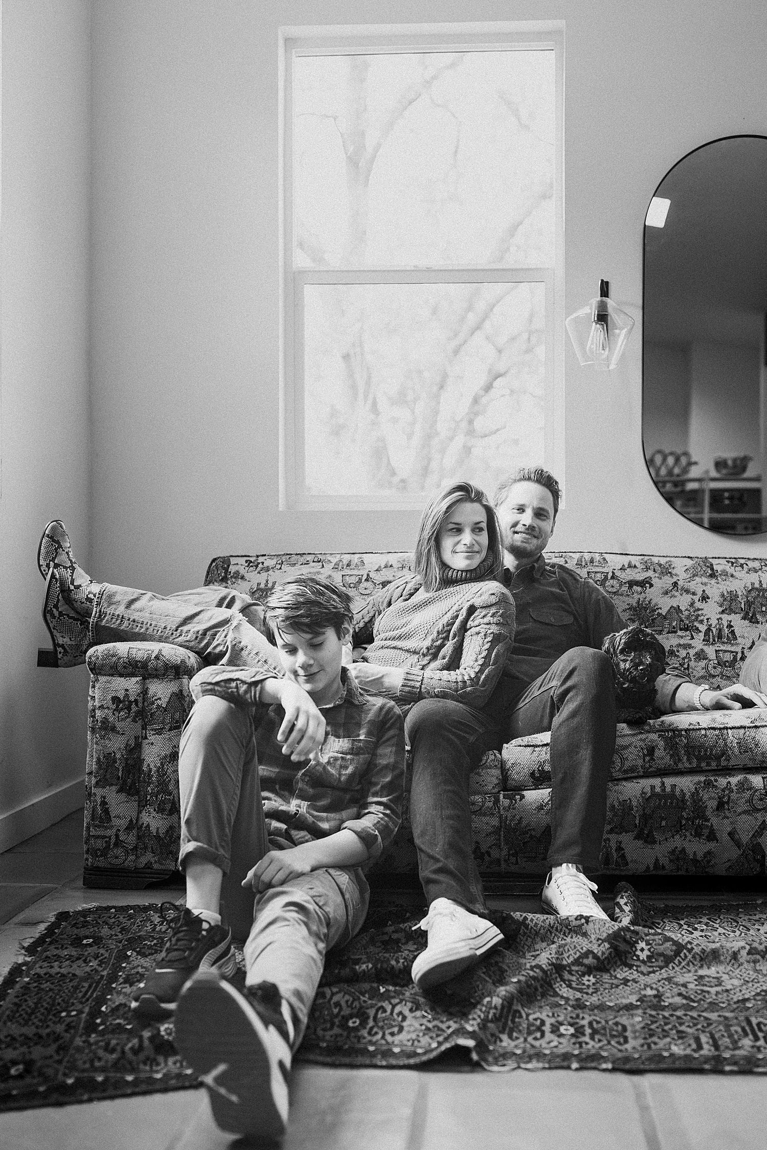 mom and dad sit on couch with son on floor by Austin family photographer
