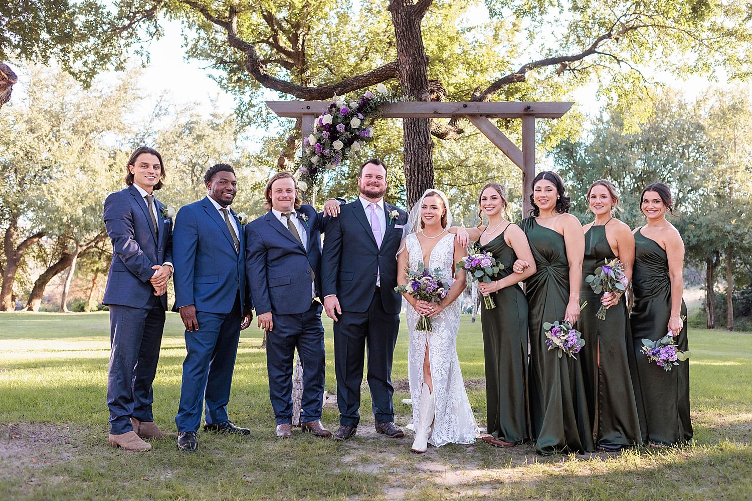 bridal party on the lawn under a wooden arch by Austin wedding photographer