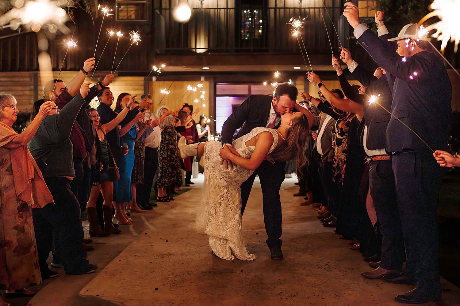 man dips his new wife for a kiss in sparkler exit in Texas Hill Country